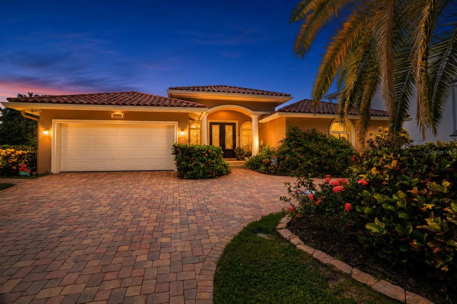Welcome to 2001 Illinois Ave NE, where elevated waterfront living meets the timeless appeal of Venetian Isles. Ideally positioned in one of St. Petersburg’s premier boating communities, this 5-bedroom, 4.5-bathroom, 3,405-square-foot residence offers a rare combination of space, privacy, water views, a private pool, dock, and peace of mind — with an elevated ground-level design that has never flooded, including during Hurricane Helene.

From the moment you arrive, the circular paver driveway, welcoming front porch, and hurricane-rated windows and sliding doors set the tone for a home built for both comfort and confidence. Inside, the layout unfolds beautifully with two expansive living areas designed for gathering, entertaining, and everyday luxury. The front of the home features a gracious foyer with raised ceilings, formal living room, and dining room, while the rear of the home opens into the heart of the property — a spacious kitchen and family room with vaulted ceilings, abundant natural light, and views that draw you toward the canal and beyond.

The kitchen is designed to be both functional and inviting, offering granite countertops, a large island with sink, cabinet storage, seating for four, stainless steel appliances, a gas cooktop with range hood, convection microwave and oven, Bosch dishwasher, trash compactor, refrigerator, and a wet bar with bar fridge. Wood cabinetry with under-cabinet lighting, glass-front display cabinets with interior lighting, a swing-out pantry organizer, spice rack, and built-in desk add thoughtful details throughout.

The bedroom layout offers exceptional flexibility, with three bedrooms featuring en-suite bathrooms — a rare find in a home of this size and setting. The owner’s suite provides a private retreat with an en-suite bath and sliding glass door access to the patio and pool. Two junior suites each include their own en-suite bathrooms, creating ideal accommodations for family, guests, or multigenerational living. Two additional bedrooms, including one with a built-in desk perfect for a home office or flex space, share the hall bathroom. The remodeled 2025 interior laundry room features new upper cabinets, a utility sink cabinet, Smart 2025 washer and dryer, and a countertop for additional storage.

Out back, the home truly comes to life. Mature landscaping creates a sense of privacy around the pool, while the covered back and side patios invite you to relax, dine, and entertain with peaceful canal views. The pool area and patio were remodeled in 2022 and feature travertine pavers, new pool tile and coping, marcite finish, swim benches, and a paver walkway to match the driveway. The composite dock, completed in 2023, features a 12x18 upper deck and 3x18 lower landing, paired with 96 feet of seawall and direct access to the waterways leading toward Tampa Bay and Weedon Island.

Additional features include upgrades designed to provide peace of mind from storms and flood waters, including a raised foundation encompassing the living area, garage, pool, and patio. Impact windows and doors, a front door hurricane curtain, and a secondary electric panel powered by a portable generator further enhance the home’s comfort and security. Other recent updates include two zoned A/C systems, replaced in 2023 and 2024, and fresh exterior paint completed in 2025.
