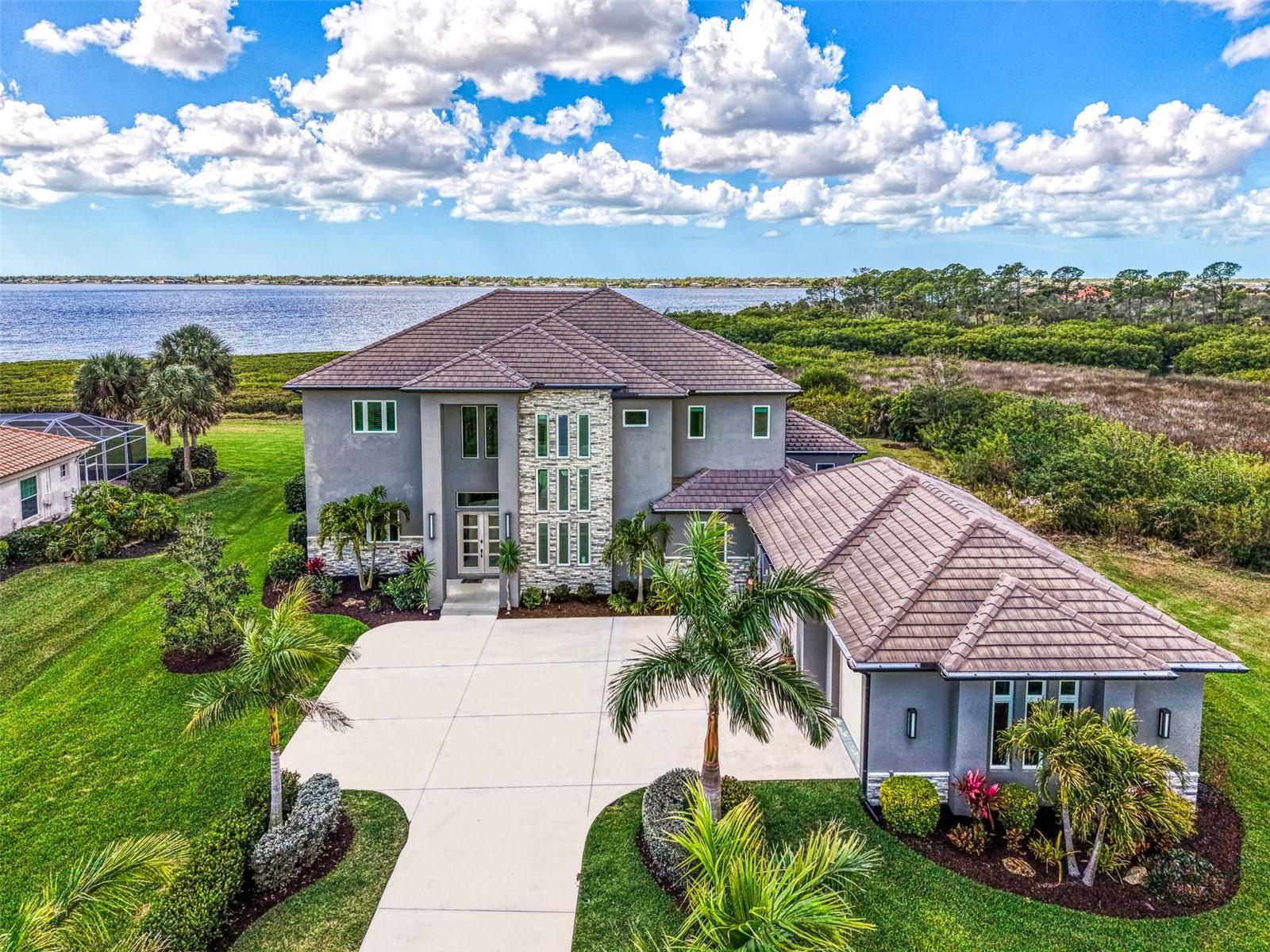 RIVERSIDE of RIVERWOOD – Exclusive Modern Florida Living on a Grand Scale. Captivating panoramic views of the Myakka River, lush preserves, and breathtaking sunsets are enjoyed from every level of this spectacular 2021-built riverfront estate. This well-constructed two-story residence with private elevator offers 4 bedrooms, 4.5 baths, a den, and over one acre of prime waterfront property, truly a rare riverfront jewel. From the moment you arrive, the architectural curb appeal impresses. An extended palm-lined driveway leads to an oversized three-car garage plus golf cart bay. The welcoming foyer opens to a dramatic great room with soaring 22-foot coffered ceilings and a wall of glass framing the expansive lanai, resort-style pool and spa, and tranquil river beyond. Contemporary design, superior craftsmanship, and designer lighting, window treatments, tile, fixtures, and flooring are showcased throughout. The gourmet kitchen is designed for entertaining, offering sprawling granite countertops, oversized center island, wet bar, walk-in pantry, top-of-the-line appliances, and adjacent formal dining. Tray ceilings, abundant windows, and sliding glass doors flood the home with natural light, creating seamless indoor-outdoor living. The main level features a private en-suite bedroom, den with direct lanai access, second bedroom ideal as an office, half bath, and ample storage. Outdoor living is exceptional with a fully equipped kitchen with gas grill and smoker and convenient full pool bath. Ascend the decorative wood staircase or elevator to the second-floor primary retreat featuring a private balcony overlooking the river, dual walk-in closets and vanities, freestanding tub, and expansive Roman shower. An additional guest bedroom with full bath and upstairs laundry complete the level. Additional highlights include impact-rated hurricane and UV-protected windows and doors, handicap-accessible baths, whole-house oversized generator, and 1,000-gallon propane tank. Residents enjoy private fishing, canoeing, and kayaking from the Riverside pier with frequent dolphin, snook, and redfish sightings.Located within Riverwood, a premier resort-style community offering Riverwood Golf Club, activity center with lap and resort pools, fitness center, pickleball, tennis, croquet, bocce, art room, library, dog parks, and vibrant social events. Optional memberships available for golf, dog park, and private beach club on Manasota Key. Ideally located near spring training for the Tampa Bay Rays and Atlanta Braves, Gulf beaches, Charlotte Harbor, Punta Gorda, Venice, Englewood, and Boca Grande, positioned between Sarasota and Fort Myers. A rare opportunity to own a magnificent riverfront estate blending coastal elegance, nature, and luxury resort living.