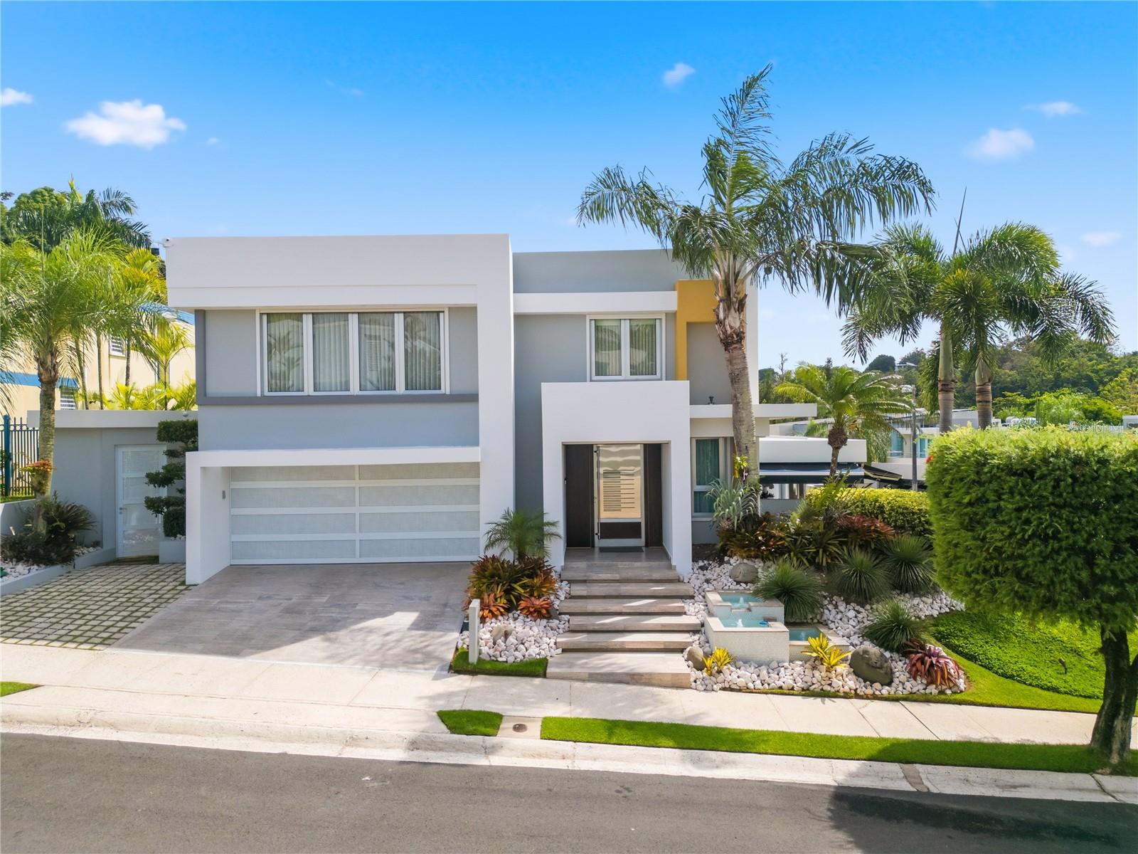 Exceptional fully remodeled residence located in the gated community of Árboles de Montehiedra. This smart home offers approximately 5,049 interior sq. ft. plus covered terrace areas, featuring 4 bedrooms, 5 full bathrooms, and 1 half bath. Originally expanded beyond its original footprint, the residence showcases spacious living areas, marble floors, designer lighting, custom finishes, and a kitchen equipped with top-of-the-line Monogram appliances, oversized island, and wine display. The property also includes a private gym area and a primary suite featuring steam and sauna amenities. The property includes smart-home integration controlled from an iPad or mobile device, managing lighting, sound, central air conditioning, motorized curtains, electric shutters, security cameras, alarm system, and more. Outdoor spaces include a covered terrace, heated pool, lush landscaping, and entertainment areas. Additional features include sound system throughout the home, full power generator, four 600-gallon cisterns, inverter A/C units in guest bedrooms, and extensive upgrades throughout. Turnkey property located in one of San Juan’s most exclusive gated communities.