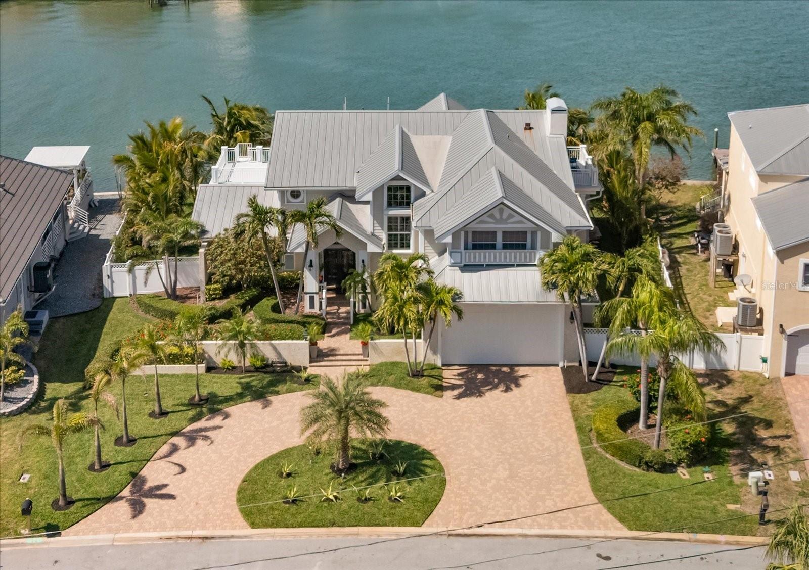 Welcome Home to the Best of Waterfront Living (rare 111 ft wide lot), delightfully elevated and never flooded, on the Intracoastal waterway, just steps from resident private access to the most beautiful sugar sand beaches in Florida! Your waterfront paradise is nestled in a richly landscaped yard full of lush, fruiting coconut palm trees in an inviting tropical setting. Enjoy the greatest boating waters that Florida has to offer from your own private 20,000 pound high speed lift, sailboat waters, or jet around from two jet ski lifts on a 10,000 pound lift - all new and never used. Enjoy sunset views of the Gulf from your new forever dock, poolside (salt water), from the separate spa, screened lanai or one of the second floor open decks.  Yes, you can see the Gulf from here! While inside, two new HVAC units will keep you cool and comfortable. Natural lighting complements the elegance of your home built for entertaining and comfort. Water views greet you from the time you enter the double front doors. Formal living and dining hosts high style dinner parties while a large open kitchen, great room and wet bar brings family and friends together around the oversized gas fireplace. Upstairs, enter your primary suite retreat with large sitting area and private terrace, walk-in shower, jetted tub, dual sink vanity, walk in closet and windows facing every direction. The fourth bedroom is large enough for a media room, office and exercise equipment...a rare find on the beach. Ample closet space and plenty of storage throughout the home and a freshly refinished garage with door height to house the tallest vehicles. There's plenty of parking too with deep driveway and circular drive that welcomes your guests as they arrive. Come Home to 213 Harrison Ave and the Crown Jewel of Belleair Beach!