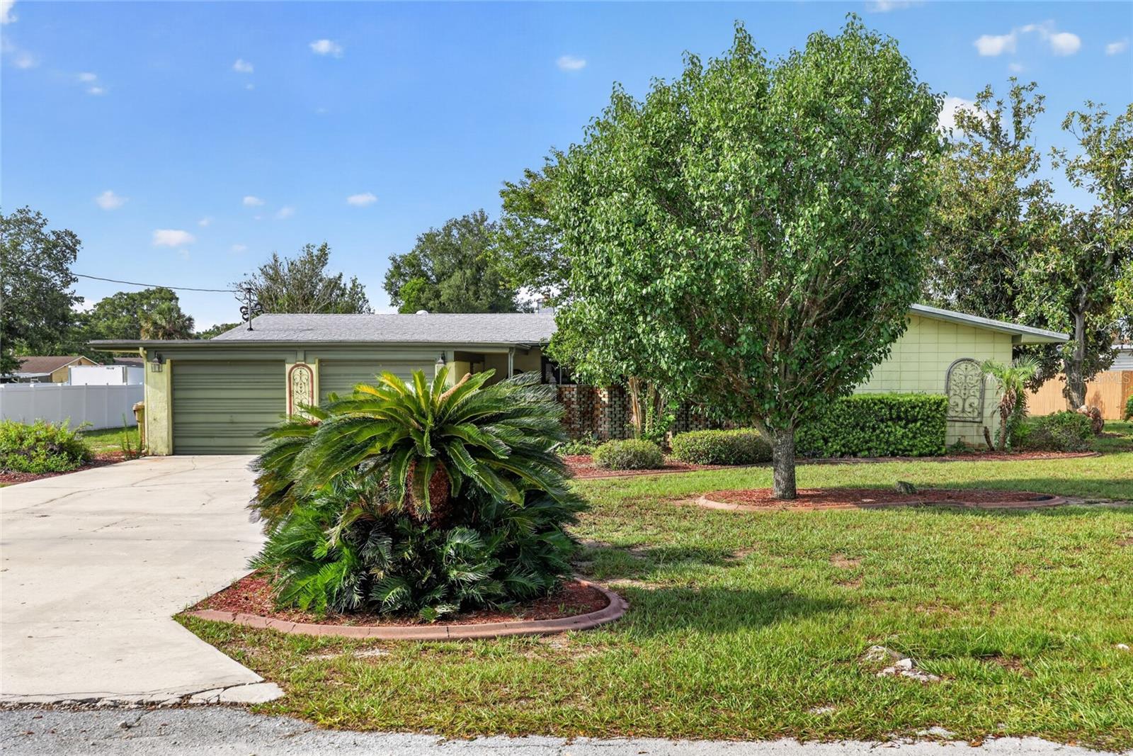 Virtually Staged. Welcome to PICCIOLA ISLAND — an ALL-AGES community with a LOW OPTIONAL HOA and ACCESS TO THE COMMUNITY BOAT RAMP ON LAKE GRIFFIN, part of the HARRIS CHAIN OF LAKES. This solid mid-century style CONCRETE BLOCK 3BR/2BA home with OFFICE sits on a 0.41 ACRE LOT and brings BIG UPDATES including a 2023 ROOF, 2022 HVAC, and 2025 SEPTIC DRAINFIELD.
Offering 1,738 SQ FT, the layout features a spacious 26x14 LIVING ROOM with WOOD-BURNING FIREPLACE, solar tubes, brick accents, and double doors to the FRONT COURTYARD/ZEN GARDEN. The OFFICE/DEN includes abundant NATURAL LIGHT from three windows.
The UPDATED KITCHEN showcases CORION COUNTERTOPS, STAINLESS STEEL APPLIANCES, pull-outs, pantry nook, built-in COFFEE BAR/BUFFET, display cabinets, and an arched pass-through to the FAMILY ROOM. The FAMILY ROOM opens to the backyard and the private primary suite with FRENCH DOORS. The en-suite includes a SOLAR TUBE, CORION vanity, LINEN CLOSET, and a STEP-IN TILED SHOWER WITH GLASS DOOR. Additional highlights include a 19x12 FLORIDA ROOM, Laundry/Utility Room with Washer & Dryer, an ENCLOSED 2-CAR CARPORT turned GARAGE (no auto doors), EXPANDED DRIVEWAY, backyard pergola, mature landscaping, and PUBLIC WATER with SEPTIC. Bedrooms are generously sized with built-ins, and the guest bath features a JACUZZI TUB.
This quiet island community offers optional social events and the perfect blend of SPACE, UPDATES, CHARACTER, and LAKE ACCESS. Conveniently located in Fruitland Park near Leesburg and The Villages, FL, with easy access to shopping, dining, healthcare, and entertainment. Don’t miss this unique home with SO MUCH CHARACTER — and be sure to watch the attached video and drone footage!