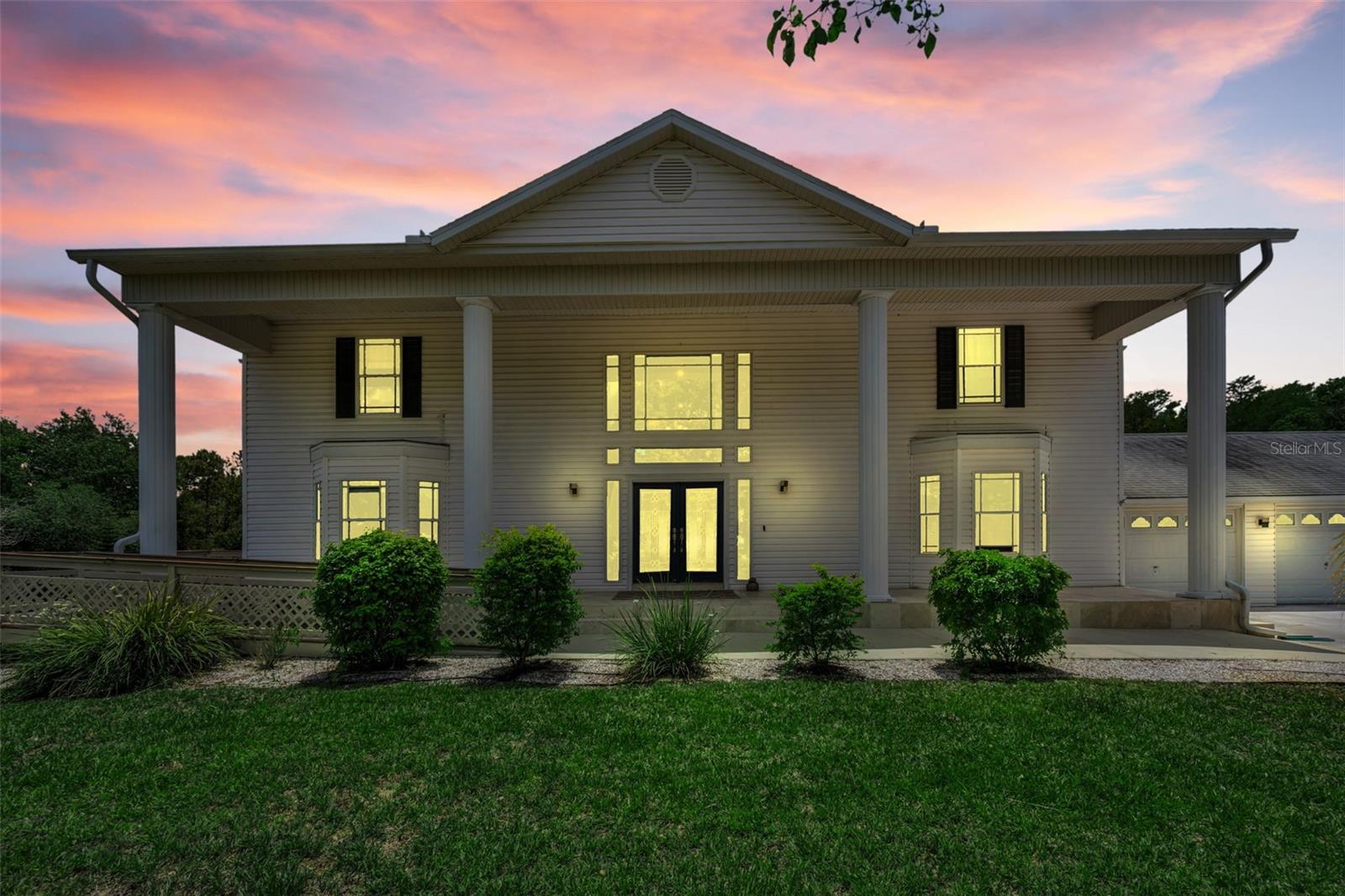 Tucked away on 4.25 private acres in the sought-after Golden Acres community of New Port Richey, this extraordinary estate offers over 5,300 sq. ft. of refined living space, 5 bedrooms, 4.5 baths, a 3-car attached garage, and an unforgettable resort-style pool experience. A welcoming front porch with stately pillars, dual bay windows, and elegant double glass front doors create a striking first impression. Inside, the thoughtfully designed layout blends sophistication and comfort with a formal dining room opening to the spacious living room, accented by French doors leading to the outdoor oasis.
The beautifully appointed kitchen is designed for both entertaining and everyday living, featuring granite countertops, a center island, eat-in dining space, and high-end stainless steel appliances. An open staircase leads to the upstairs loft/office complete with built-in shelving and storage. The expansive primary suite offers a luxurious retreat with dual vanities, a massive walk-in tile shower, and an oversized walk-in closet. Generously sized guest bedrooms provide exceptional comfort, including one with its own ensuite bath. A private rear deck overlooks the peaceful backyard setting.
Ideal for multigenerational living or guests, the separate in-law suite features its own private entrance, full kitchen, living area, 2 bedroom, and 2 bath with walk-in shower. Downstairs, an enormous flex space includes a dedicated movie room and half bath, offering endless possibilities for recreation, fitness, or entertaining.
Step outside to the showstopping screened lanai and spectacular custom pool area designed for luxury living. Complete with a swim-up table, sun shelf, waterfall feature, and expansive covered outdoor living space, this backyard retreat delivers the ultimate Florida lifestyle. Conveniently located near top-rated schools, shopping, dining, golf courses, parks, and Gulf beaches, this exceptional Golden Acres estate offers privacy, elegance, and resort-style living all in one remarkable property.