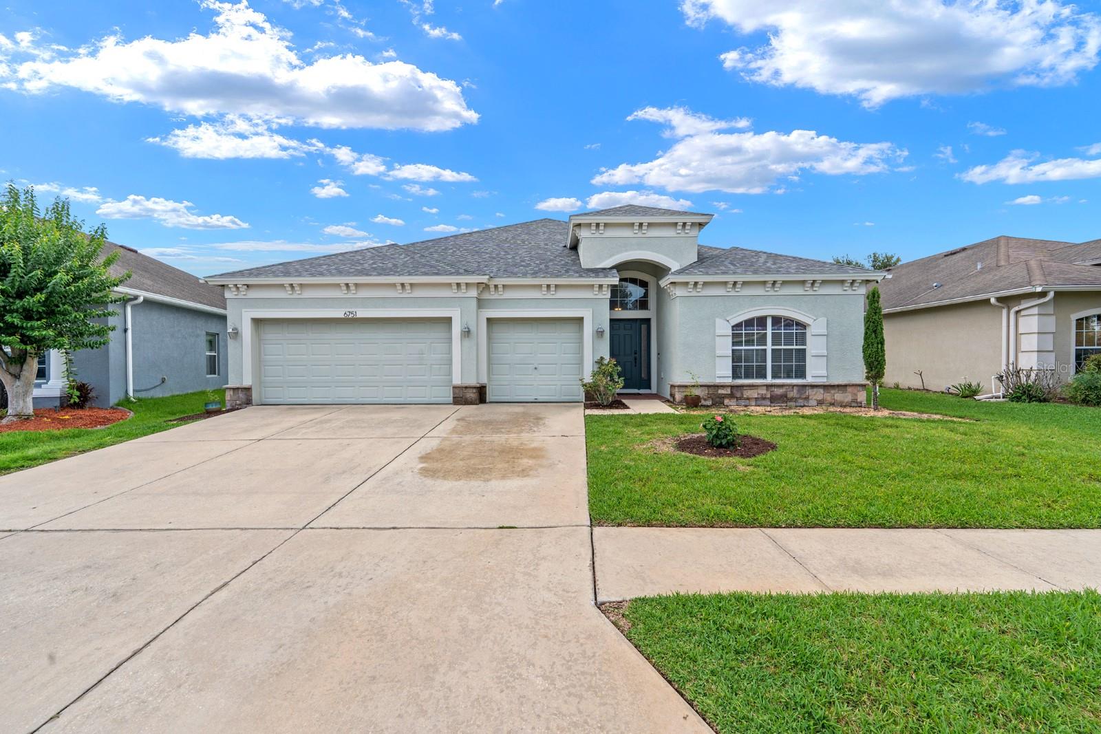 Move-in ready waterfront home in the highly sought-after Oak Creek community! This beautifully maintained 4-bedroom, 3-bath, plus office/den home offers 2,382 sq ft of thoughtfully designed living space and a desirable 3-way split floor plan. Major updates include a NEW ROOF and NEW A/C, providing peace of mind for years to come. Inside, you'll find soaring ceilings, engineered wood flooring, formal living and dining areas, and an open-concept family room overlooking tranquil pond views. The spacious kitchen features 42" wood cabinetry, stone countertops, stainless steel appliances, a breakfast bar, and a cozy dinette area. The private primary suite is tucked away from the secondary bedrooms, creating a relaxing retreat. Step outside to the oversized covered lanai with epoxy flooring and a large hot tub, perfect for entertaining or unwinding while enjoying beautiful waterfront views. The fully fenced backyard offers added privacy. Additional features include a 3-car garage and whole-home water softener. Low HOA fees and outstanding community amenities, including a resort-style pool, playgrounds, basketball and tennis courts, and a dog park. Conveniently located near top-rated schools, shopping, dining, hospitals, entertainment, and I-75. Don't miss this exceptional opportunity in one of Wesley Chapel's most desirable communities!