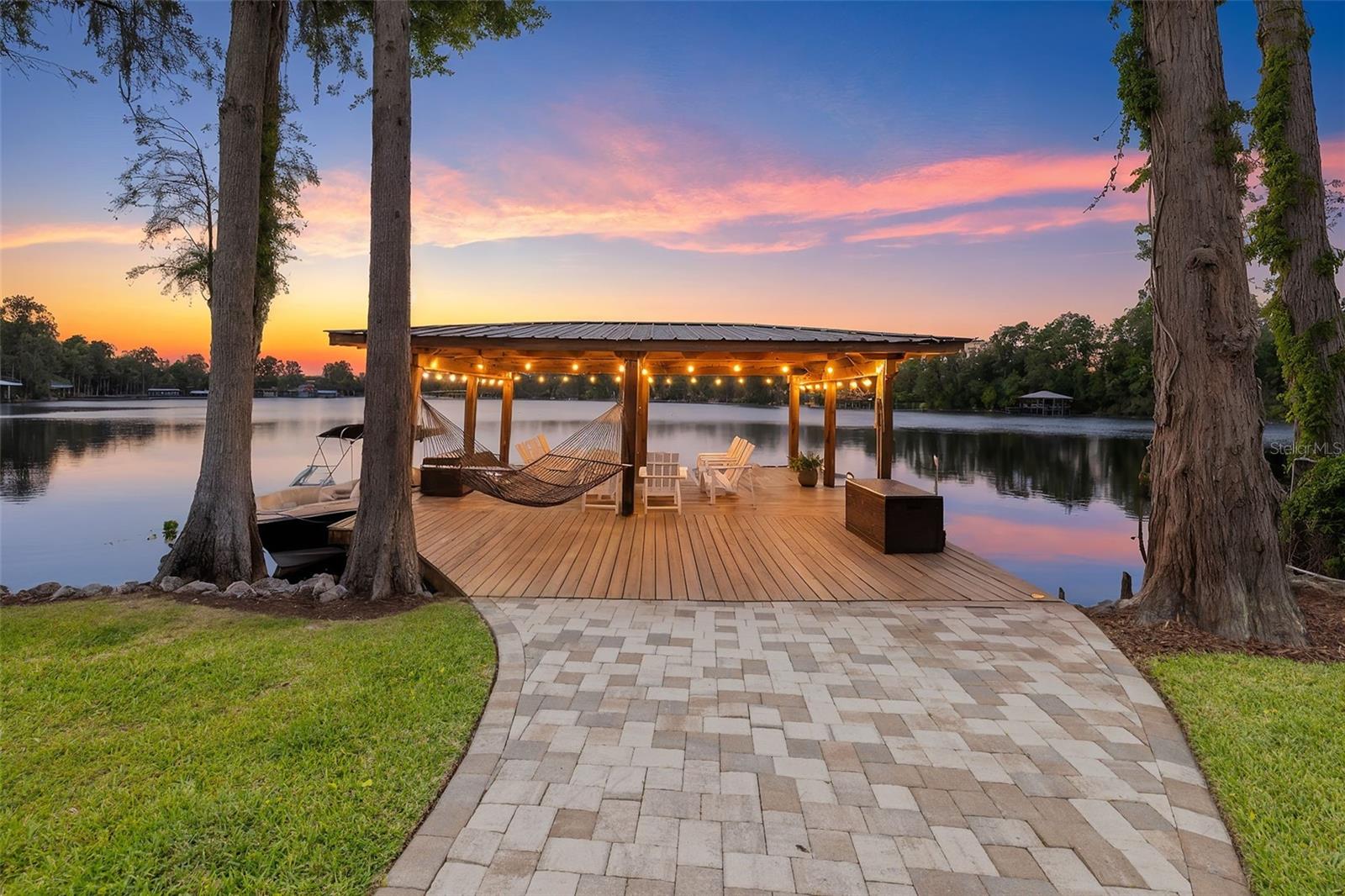Welcome to 18520 Wayne Rd in Odessa, where lake living on Lake Keystone becomes your everyday reality. Set on a .57-acre lot with direct water access and western exposure for sunsets, this beautifully updated home offers the perfect blend of comfort, style, and the unmatched lifestyle that Lake Keystone is known for. Spanning approximately 434 acres, Lake Keystone is one of the area's most sought-after private ski lakes, ideal for boating, jet skiing, fishing, and sunset cruising, all within a peaceful, scenic setting just minutes from Tampa. Enjoy the freedom and flexibility of lakefront living with NO HOA and NO CDD. Featuring 4 bedrooms, 3 full bathrooms, and nearly 3,000 sq ft, this home offers an open floor plan designed for both everyday living and entertaining. The garage was redesigned to include a bedroom, full bathroom, living room, and separate entrance, making it a perfect space for an in-law suite or guest suite. Thoughtfully updated throughout, the home shows like new with a fresh, warm, and inviting feel. The kitchen, remodeled in 2017, showcases granite countertops, Whirlpool Gold appliances, and flows seamlessly into the main living spaces for a bright and welcoming atmosphere. Inside, the home offers a crisp, cohesive aesthetic with plantation shutters, updated finishes, and expansive double-pane windows (replaced in 2020) that frame serene lake views. The spacious primary suite has been thoughtfully remodeled and provides a peaceful retreat overlooking the water, while a private guest suite offers comfort and flexibility for visitors. Step through the rear French doors and the lake immediately becomes your backdrop. A beautifully designed paver walkway leads you through the lush backyard to your private covered dock, creating a seamless transition from indoor living to the outdoors. Along the way, multiple seating areas offer the perfect setting to relax, entertain, and take in the views of the property's 84 feet of lake frontage. The covered dock sits on the lake and is ideal for boating, jet skiing, fishing, or simply unwinding as the sun sets over the water. From morning coffee by the water to evenings spent on the dock, this home is designed to fully embrace the Lake Keystone lifestyle. Recent updates and improvements include: remodeled kitchen in 2017, double-pane windows replaced in 2020, primary suite remodel, guest suite enhancements, remodeled laundry room, updated bathroom, new exterior doors in 2021, new landscaping in 2023, paver driveway and walkway, and fresh exterior paint completed in 2025. Located just 15 to 20 minutes from downtown Tampa, you'll enjoy easy access to top dining, shopping, and entertainment while still coming home to a quiet, private waterfront setting. Discover lakefront living with space to relax, entertain, and be on the water whenever you choose. Homes like this on Lake Keystone do not come around often — a rare combination of location, thoughtful updates, and direct water access.