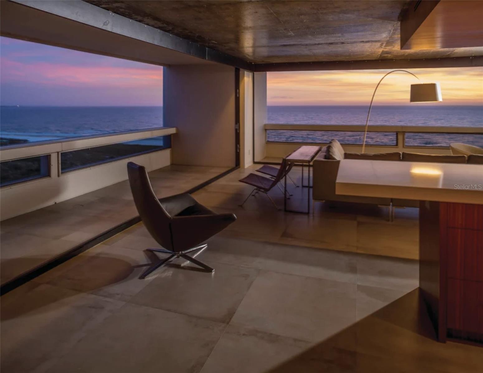 Perched 15 floors above the Gulf of Mexico within The Terrace—Frank Folsom Smith's iconic beach-front landmark on Siesta Key—two corner residences were combined to create an extraordinary 2,365-SF home. Completely reimagined by award-winning architect Michael Halflants of Halflants + Pichette Studio for Modern Architecture, the residence received the prestigious AIA Florida/Caribbean Honor Award of Excellence in Interior Design and was featured in Sarasota Magazine's Dream Homes issue.
Original interior walls were removed to reveal uninterrupted vistas that extend along the shoreline of Siesta Key, across Sarasota Bay, and to the downtown Sarasota skyline. The result is a flowing two-bedroom, two-and-a-half-bath residence where panoramic views, exceptional materials, and thoughtful design exist in perfect balance.
At the center of the home, a sculptural Etimoe hardwood core houses the kitchen, storage, primary bath, and an expansive walk-in closet, bringing warmth and architectural definition to the open floor plan. Floor-to-ceiling, seven-panel bi-fold glass doors disappear completely at the corners, creating a seamless connection to the Gulf and inviting coastal breezes into the living spaces. Custom folding partitions provide privacy between the primary suite and main living areas without compromising the home's openness or visual continuity. Thoughtful custom details continue throughout the residence, including a custom steel desk overlooking the Gulf of Mexico, creating a work-from-home setting few could rival.
The raw concrete ceiling from Smith's original 1969 design was scraped and clear-coated to a soft sheen, transforming a defining element of the building into a striking contemporary feature. Large-format porcelain tile, custom steel detailing, and carefully selected wood finishes complete a sophisticated material palette that feels both timeless and contemporary.
Residents of The Terrace enjoy private access to Siesta Key's renowned beach and are just moments from the shops, restaurants, and energy of Siesta Village. More than a luxury beachfront residence, this is a rare opportunity to own an award-winning home within one of Sarasota's most recognizable waterfront landmarks, where exceptional architecture and Gulf-front living are seamlessly intertwined.