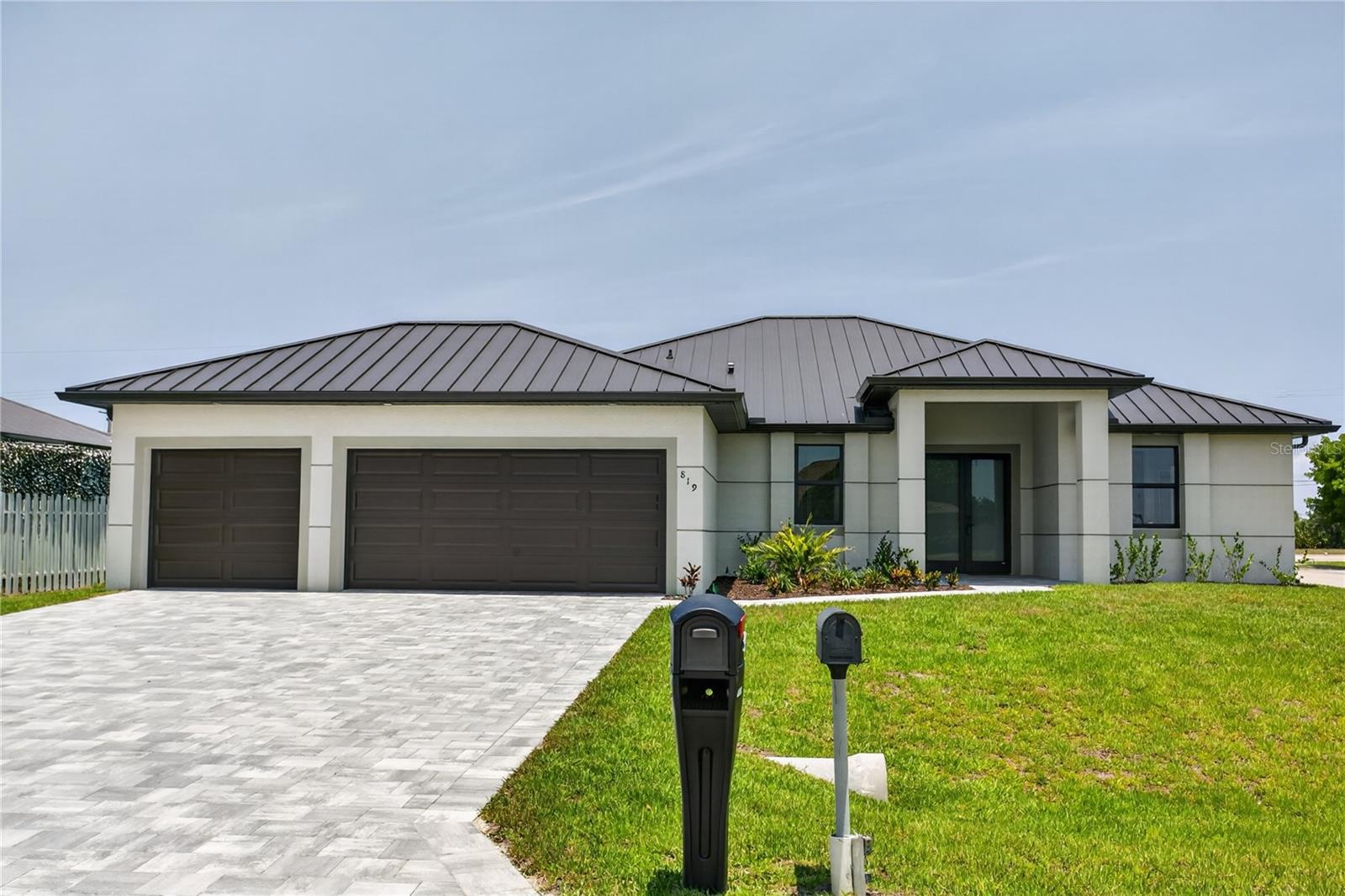 Embrace MODERN COASTAL ELEGANCE in this stunning SWFL retreat! Move-in-ready NEW CONSTRUCTION HOME (2026) complete w/ 2-10 HOME WARRANTY! Located in SW Cape Coral, offers NO FLOOD INSURANCE, durable METAL ROOF, 3-CAR GARAGE & CITY WATER & SEWER! $1,800-$2,400/year homeowners' insurance! Enjoy easy access to SKYLINE BLVD & TRAFALGAR PKWY, making commuting & daily errands easier! This CONTEMPORARY LUXURY HOME features SCREENED, HEATED POOL & SPA & 4 BEDS (2 primary suites) & 3 full BATHS, layout is ideal for EVERYDAY LIVING & ENTERTAINING! SCREENED LANAI provides PERFECT SETTING TO RELAX in SPA, SWIM in HEATED POOL, or HOST UNFORGETTABLE BBQs while enjoying THE BEST OF SWFL LIVING! Bright, open layout w/ LIGHT NEUTRAL TILE FLOORING throughout. IMPACT-RESISTANT DOUBLE DOORS lead into WELCOMING LIVING ROOM w/ 12-ft VAULTED CEILING & SLIDING DOORS TO LANAI. GORGEOUS CHEF’S KITCHEN showcases sophisticated CUSTOM CABINETRY w/ rich TWO-TONE cabinetry showcasing sleek EUROPEAN-INSPIRED design w/ DEEP ESPRESSO WOODGRAIN lowers paired w/ CRISP MATTE WHITE cabinetry for a clean MODERN aesthetic. Crisp QUARTZ COUNTERTOPS & matching FULL BACKSPLASH complement modern palette, while UNDER-CABINET LED LIGHTING enhances the bright, open feel. Equipped w/ SS appliances, French-door refrigerator, microwave, smooth-top range & angular EURO-STYLE hood & dishwasher. Oversized ISLAND & minimalist HARDWARE-FREE CABINETRY. Built-in BUTLER’S PANTRY w/ DEEP ESPRESSO WOODGRAIN cabinetry, sleek WHITE upper cabinets, QUARTZ countertops, under-cabinet lighting & built-in WINE REFRIGERATOR, ideal for BEVERAGE STATION, COFFEE BAR, EXTRA STORAGE or PREP SPACE. DINING ROOM w/ bright, modern design, deep contrasting tones & vaulted ceiling w/ recessed lighting that enhances open feel. LARGE PICTURE WINDOW brings in natural light & offers views screened lanai & pool/spa. LARGE PRIMARY SUITE w/ sliding doors to lanai, WALK-IN CLOSET w/ BUILT-IN SHELVING & HANGING RACKS & LUXURIOUS PRIMARY BATHROOM w/ spacious WALK-IN GLASS SHOWER w/ floor-to-ceiling designer tile, rainfall showerhead, built-in bench & modern matte-black fixtures. Dual sink vanity w/ quartz countertops, sleek white cabinetry & contemporary lighting complete spa-like design. Private water closet & generous natural light create BRIGHT & SERENE RETREAT! BUILT-IN CUSTOM CLOSET WHITE CABINETRY provides ADDED STORAGE & CLEAN, UPSCALE LOOK. SPLIT LAYOUT offers SECOND PRIMARY SUITE w/ POOL BATHROOM & TWO GUEST BEDROOMS w/ HALL BATHROOM, added privacy. Step outside to SCREENED LANAI w/ HEATED POOL & SPA, landscaped surrounding & FULLY EQUIPED OUTDOOR KITCHEN w/ BUILT-IN stainless steel BBQ GRILL, SINK, BEVERAGE REFRIGERATOR, GRANITE COUNTERTOPS & MODERN BACKSPLASH, ideal OUTDOOR DINING & ENTERTAINING! PAVER FLOORING & CEILING FAN create COMFORTABLE SPACE for YEAR-ROUND ENJOYMENT. LAUNDRY, 3-CAR GARAGE & long-lasting METAL ROOF complete HOMES' FUNCTIONAL FEATURES. Exceptional CORNER LOT location w/ unmatched SWFL convenience!