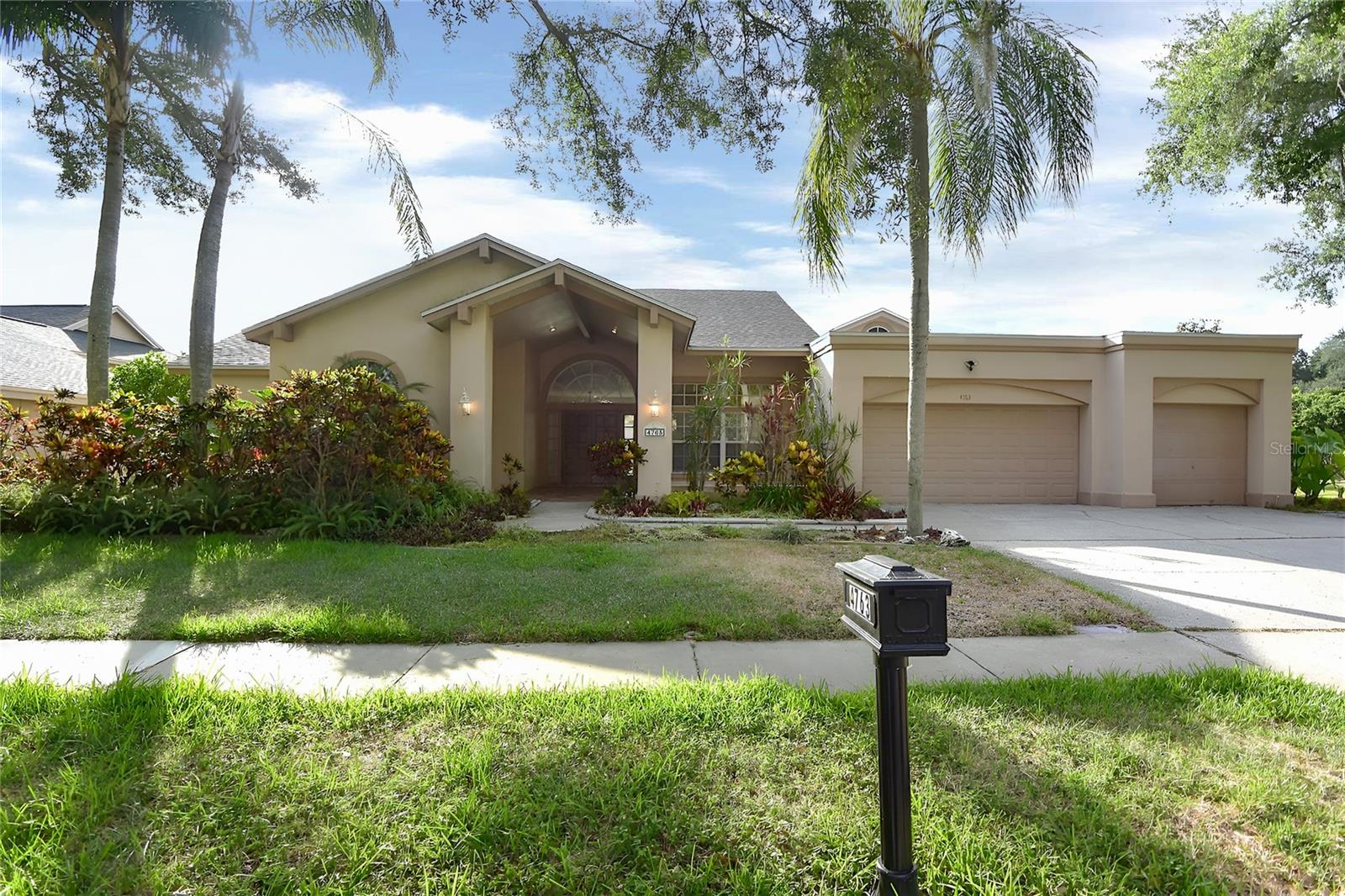 Virtually Staged. Welcome home to this spacious five-bedroom, three-bath, three-car garage pool home perfectly situated on a tranquil pond in one of Palm Harbor's most desirable communities. Designed with both comfort and functionality in mind, this home features a split-bedroom floor plan and a versatile bonus room that can serve as a den, home office, playroom, or easily become a sixth bedroom by adding a closet. You'll love the inviting front porch with beautiful terracotta tile, soaring ceilings, elegant crown molding, and attractive laminate flooring throughout the main living areas. The spacious family room is highlighted by a cozy wood-burning fireplace, while the dinette overlooks the sparkling pool, in-ground spa, and peaceful pond views. The oversized primary suite offers a relaxing retreat, and the generously sized secondary bedrooms provide plenty of room. Additional features include an inside utility room, an oversized three-car garage, and a huge covered rear porch that's perfect for entertaining or simply enjoying Florida's outdoor lifestyle. Conveniently located near excellent shopping, restaurants, and everyday conveniences, this home also offers an easy commute to Clearwater and throughout the Tampa Bay area. Best of all, the property is zoned for highly rated schools, making this an exceptional place to call home.