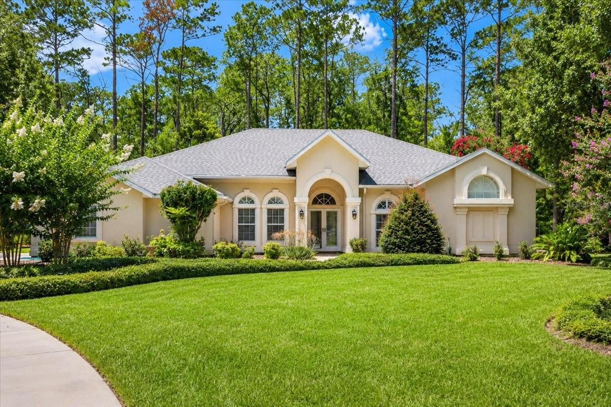 Situated on a quiet cul-de-sac in the highly desirable Ashton community off scenic Millhopper Road in NW Gainesville, this meticulously maintained custom-built home offers just under 3,000 sf of thoughtfully designed living space on a beautifully landscaped half-acre homesite backing to conservation land, including San Felasco Preserve. This contemporary 4-bedroom, 2.5-bath residence is filled w/ abundant natural light, soaring ceilings, and expansive windows that create a bright, airy atmosphere. Timeless architectural details—including custom built-in cabinetry, granite countertops, elegant foyer columns, arched windows, and a floor-to-ceiling stone fireplace—blend seamlessly with numerous modern updates. Recent improvements include luxury vinyl plank flooring, whole-house repiping, a tankless water heater, a new roof (2025), conversion of the wood-burning fireplace to gas, plantation shutters, updated primary bathroom, enclosed Florida Room, and a sliding screen garage door. The desirable single-story floor plan features a 2-way split w/ the primary suite and an additional bedroom on one side of the home and two secondary bedrooms on the opposite wing for enhanced privacy. A welcoming foyer opens to formal living and dining rooms, while the spacious kitchen offers abundant cabinetry, a center island, and a breakfast nook.The adjoining great room, anchored by the impressive stone tile fireplace, creates a warm gathering space, and a conveniently located powder room is ideal for guests. One of the home’s standout features is the enclosed Florida Room, offering year-round enjoyment and exceptional versatility. Whether used as a dining area, reading retreat, playroom, home office, or simply a peaceful place to relax while overlooking the backyard, this light-filled space extends the home’s living area and perfectly embraces Florida’s indoor-outdoor lifestyle. The expansive backyard is designed for enjoying Florida’s outdoor lifestyle, w/ample room to create your dream pool. A dedicated pool bath is already in place, making future pool installation even more convenient. A beautiful paver patio provides the perfect setting for outdoor dining, and entertaining. Imagine enjoying your morning coffee while watching deer quietly graze along the conservation area just beyond your backyard. The level homesite is not located in a flood zone, and an irrigation system keeps the beautifully landscaped lawn lush and green year-round. Living on Millhopper Road means enjoying one of Gainesville’s most picturesque corridors, known for its majestic oak canopies, established neighborhoods, and easy access to nature while remaining close to everyday conveniences. Ashton is ideally located within walking distance of Hunter’s Crossing Shopping Plaza, where you’ll find Publix, restaurants, shopping, and a hardware store. Devil’s Millhopper Geological State Park and San Felasco Hammock Preserve State Park are just minutes away, offering some of the area’s finest hiking, biking, and natural beauty. Convenient access to I-75, UF, SFC, and UF Health makes this exceptional location perfectly balance peaceful living with unmatched convenience. Offering the perfect combination of privacy, thoughtful updates, abundant natural light, generous living spaces, and an unbeatable Northwest Gainesville location, this exceptional Ashton home presents a rare opportunity to experience the very best of Florida living.