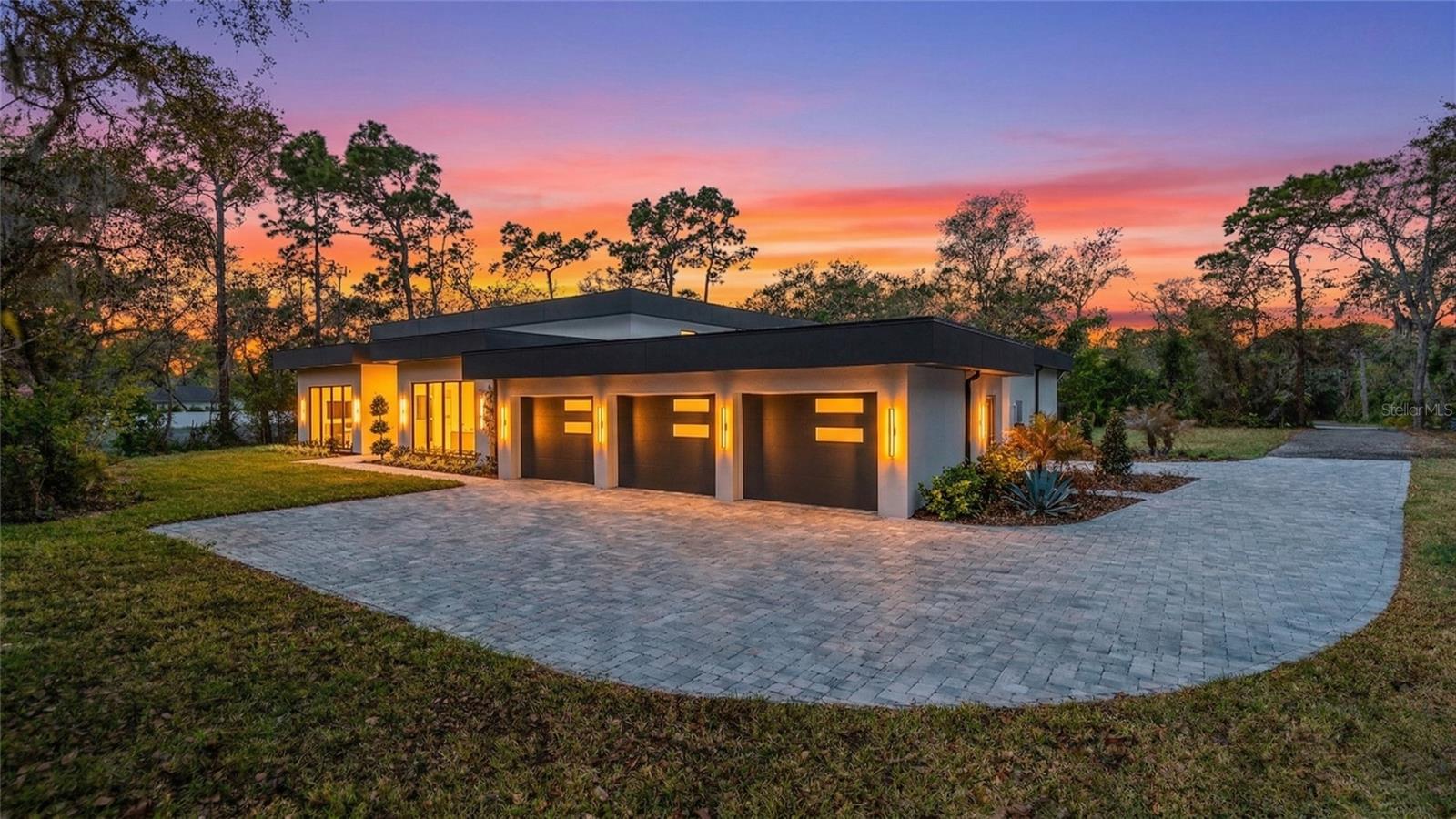 Discover the pinnacle of secluded luxury in this brand-new, 8,000 SF estate, nestled in picturesque Winter Springs. From the moment you arrive, the custom glass French entry doors hint at the artistry within. Stepping into the grand foyer, you are greeted by statement marble and mosaic flooring that sets a tone of elegance, a design narrative that flows seamlessly throughout the home.

Designed for both grand-scale entertaining and intimate daily life, the main living spaces are simply breathtaking. The great room soars with 16-foot ceilings and celestial windows, anchored by a stunning custom fireplace and bookcase display. A bank of 18-foot sliding glass doors dissolves the line between indoors and out, opening to a sprawling 1,125 SF covered patio. The chef’s kitchen is a masterpiece of form and function, featuring a 13-foot island, floor-to-ceiling cabinetry, a pet-feeding station, electric vehicle garage hookup, and a full suite of WiFi-enabled GE Cafe appliances, including a double wall oven and a 48-inch refrigerator.

The home offers a versatile and luxurious layout for multi-generational living or visiting guests, highlighted by two distinct primary suites. One wing is dedicated to a private retreat with two walk-in closets, separate vanities, and a spa-inspired wet room with a freestanding tub and a four-port shower system. On the opposite side of the home, a second primary suite offers equal luxury with a massive walk-in closet and its own spa-like wet room, ensuring complete privacy for all.

Beyond the main living areas, discover a wealth of flexible spaces tailored to a modern lifestyle. A dedicated movie theater or fitness center is pre-wired for the ultimate audio-visual experience, while two separate offices with storefront glass windows provide inspiring workspaces. A butler’s pantry/kitchen, wet bar with a beverage fridge, and a flexible flex room with a half-bath complete the impeccably designed interior.

Outside, your private paradise awaits upon the spacious 1-acre parcel. The pavered pool deck surrounds a white quartz pool with a sun shelf and bubbler, all secured by a sleek black metal fence. Every detail has been considered, from the 150-gallon propane tank servicing the future summer kitchen and pool heater to the 4-zone HVAC, a commercial grade 50-year life-span TPO roof and two tankless water heaters for ultimate comfort. This is more than a home; it is a fully realized vision of eloquent Florida living.