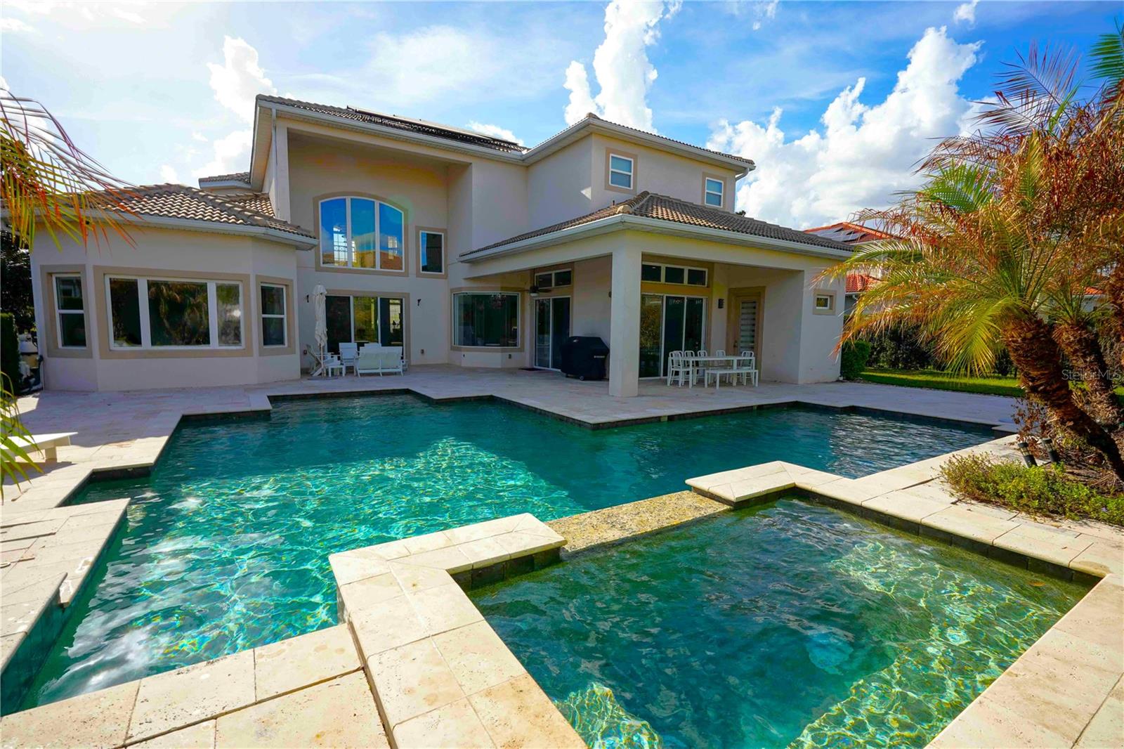 One or more photo(s) has been virtually staged. Welcome to luxury living in the guarded, gated community of Waterstone in Windermere, Florida. This exceptional residence at 6219 Tiroco Way blends elegance, comfort, and modern efficiency, featuring solar power and an impressive floor plan designed for both everyday living and entertaining.
The home offers 7 bedrooms, 5½ bathrooms, a media room, loft, dedicated office, storage room, and separate formal living and dining rooms. Elegant design elements throughout include volume ceilings, designer niches, granite countertops, stainless steel appliances, natural gas cooking, washer and dryer, an under-stairs storage closet, security system, and a spacious three-car garage. A convenient Jack-and-Jill bath with double vanity adds functionality for family or guests.
The first-floor primary suite is a private retreat featuring a spacious bedroom with a bay window overlooking the pool and two custom walk-in closets. A sitting area between the bedroom and bath provides space for comfortable chairs or a nursery setup. The luxurious primary bathroom includes dual vanities with abundant counter space, a large soaking tub, and an impressive walk-through shower with dual benches and multiple shower heads.
The kitchen is ideal for the home chef, showcasing a large center island with additional storage and two pantries. It opens seamlessly to the family room, dinette, and outdoor living area, creating the perfect layout for gatherings and daily living.
Step outside to your private backyard oasis featuring a designer custom pool and spa with waterfall and fountain features, elegant travertine decking, and plenty of space for outdoor entertaining. Two sizeable side yards offer additional room for recreation and privacy.
Waterstone is a highly sought-after community located on the shores of Lake Butler, offering 24/7 guarded security, scenic walking trails, beautiful stone accents, and distinctive architecture. Residents also enjoy a private gate to Windermere Preparatory School. Conveniently accessing Walt Disney World, one can even watch the Disney fireworks from the community. Also in proximity are area theme parks, excellent shopping and dining, and major highways including State Road 429 and the Florida Turnpike for easy travel to downtown Orlando, Orlando International Airport, and the region’s booming medical corridor.