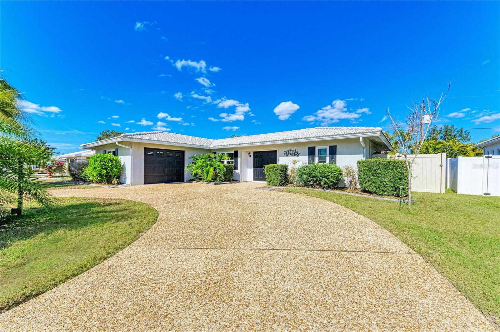 Enjoy the best of Sarasota living in this centrally located, fully fenced home with impact windows, circular driveway, with an amazing private outdoor living space that is minutes from shopping, dining, and a short drive to the sugar-sand beaches of Siesta Key. Thoughtfully updated and designed for comfortable everyday living, this home offers a flexible floor plan and inviting spaces both indoors and out.

Inside, the light and bright interior features a crisp, clean feel and a desirable split-bedroom, open floor plan. Modern light wood-look laminate flooring flows throughout the home. The entryway includes a convenient coat closet and the open dining and living room combination offers flexibility for entertaining and everyday living. The interior flows seamlessly from the front of the home through the family room and out to the enclosed lanai.
The kitchen showcases white shaker cabinets, granite countertops, a glass subway tile backsplash, and stainless steel appliances making it both stylish and functional.
The spacious primary suite features tall windows, a large walk-in closet, and an en suite bathroom that offers a shower/tub combo and a thoughtful layout with the toilet and shower separated from the vanity. The guest bedroom is generously sized, and the updated guest bathroom features tile flooring, a large stone shower with glass doors, and granite countertops.
Enjoy Florida living year-round with an enclosed, multi-use lanai featuring tile flooring and expansive glass windows that add valuable living space, along with an additional screened rear patio perfect for a more open-air outdoor experience. The vinyl-fenced backyard with lush tropical landscaping completes the home’s rear outdoor oasis.
With a great location and stylish updates throughout, this home is ready to be enjoyed. Come see it, feel the charm, and make it your own!