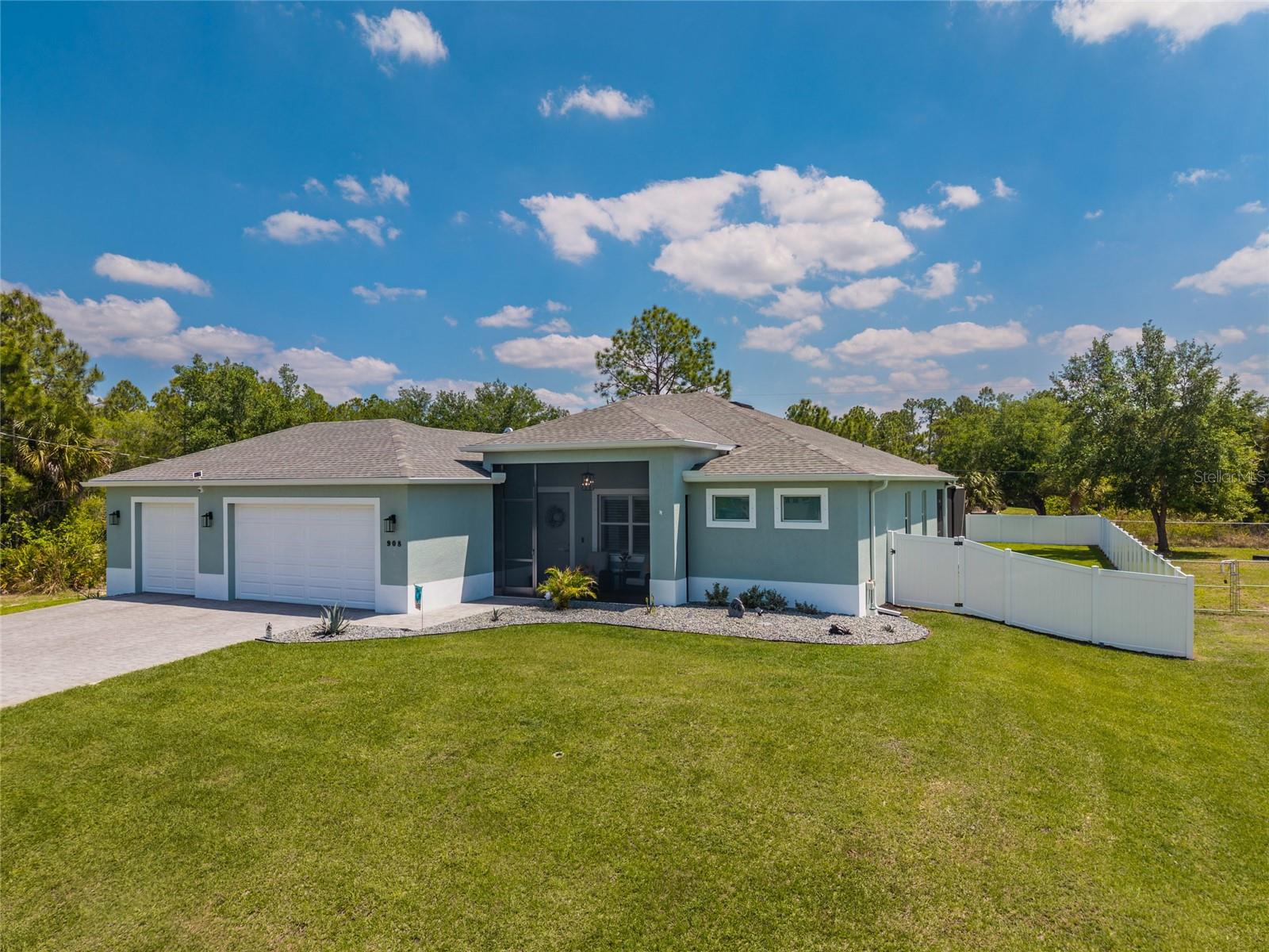 Welcome to an exceptional residence where thoughtful design, premium upgrades, and resort-style living come together in one of Lehigh Acres’ most compelling offerings. Perfectly positioned on an oversized private homesite, this fully upgraded home delivers a rare opportunity for the buyer who refuses to settle for ordinary. From the moment you arrive, the full paver driveway, manicured presentation, and impressive curb appeal set the tone for what awaits inside. Step through the front entry into a bright, open-concept interior where tray ceilings, expansive living spaces, and elevated finishes create an atmosphere of effortless sophistication. Every detail has been carefully curated, from the luxury vinyl flooring to the custom touches that make this home feel far beyond builder grade. At the heart of the home, the designer kitchen blends beauty and functionality with 42-inch soft-close cabinetry, generous workspace, and a seamless flow into the main living and dining areas—ideal for both intimate evenings and entertaining guests. The primary suite serves as a private retreat, offering comfort, style, and tranquility, while plantation shutters throughout the home add timeless character and refined elegance. Spacious secondary bedrooms and beautifully appointed baths complete a floor plan designed for modern living. Step outside and discover your own private resort. The heated, fully automated pool is surrounded by an expansive paver pool deck and screened lanai, creating the ultimate year-round outdoor oasis. Whether hosting gatherings, enjoying quiet mornings, or unwinding at sunset, this outdoor space was designed to be experienced. Beyond the beauty, the home is loaded with practical luxury upgrades including a full-house commercial reverse osmosis system, full-yard irrigation, a fully fenced backyard, and an additional storage shed for convenience. Car enthusiasts, hobbyists, and those needing extra space will appreciate the oversized 3-car garage featuring 9-foot clearance, approximately 23-foot depth, upgraded lighting, and epoxy floors, and a dedicated 60-amp EV charger connection for seamless electric vehicle readiness.. In a market filled with standard options, this is a rare one-off property where the upgrades have already been completed and the lifestyle is already in place. Move-in ready, meticulously enhanced, and impossible to replicate at this price point—this is the home that stands apart.