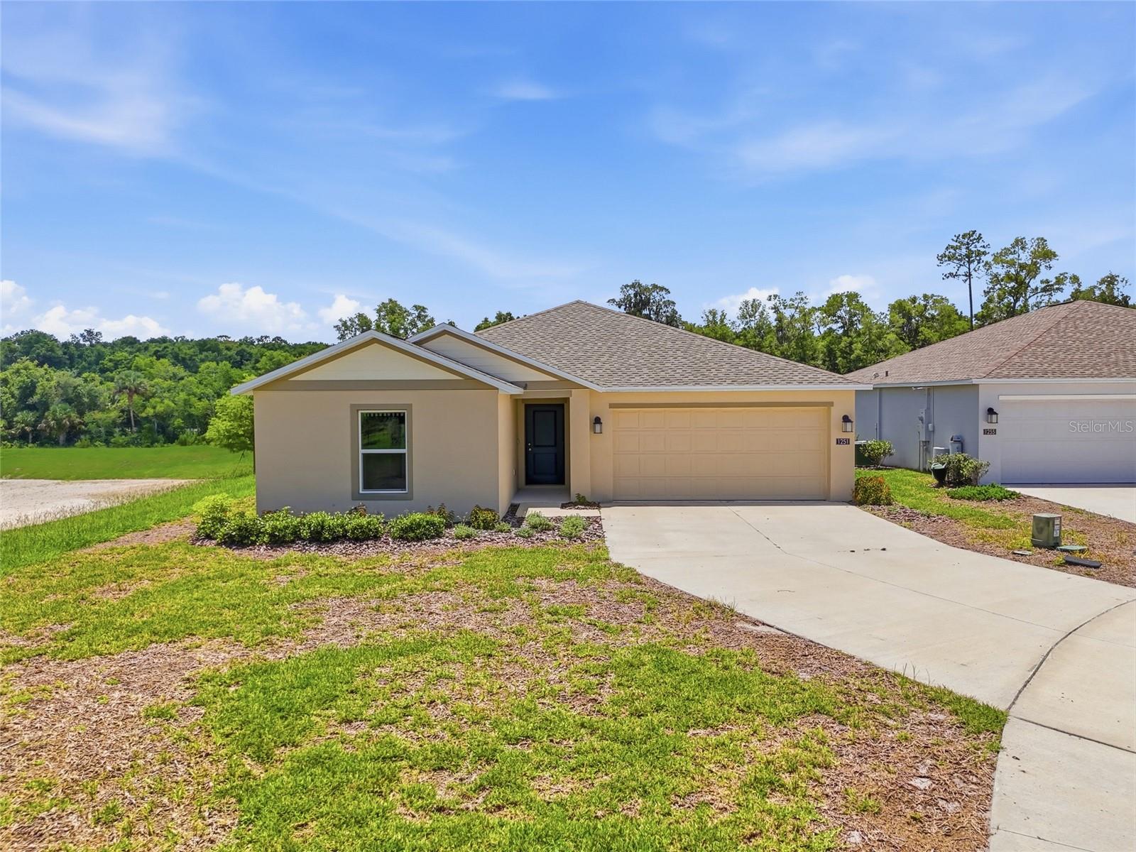 Built less than two years ago and gently lived in, this 4-bedroom, 2-bath home offers the benefits of newer construction without the wait. The single-story floor plan features an open living, dining and kitchen area with quartz countertops, energy-efficient appliances, oversized tile flooring in the main living spaces and carpet in the bedrooms. The private owner's suite is separated from the secondary bedrooms for added privacy. One of the home's standout features is its premium homesite having a wooded conservation area on two sides, providing private views from the rear windows and patio with no side or rear neighbors. Located in Oak Hammock, residents enjoy a playground, multi-use trails and convenient access to Stetson University, Blue Spring State Park, major highways and Central Florida attractions.