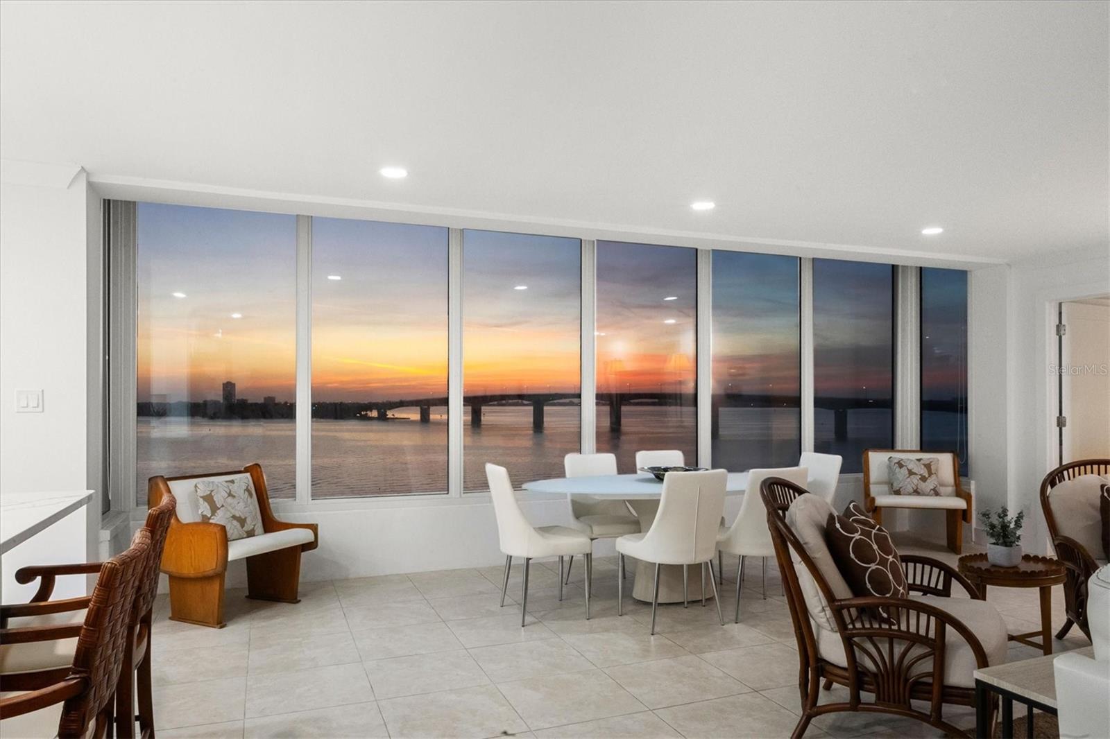 The first thing you notice is the view: a full sweep of Sarasota Bay through a wall of windows that defines the main living space. Natural light fills the open living and dining areas, where the water, the John Ringling Bridge, and the downtown skyline sit in clear, uninterrupted sight. A sizeable, light-filled great room anchors the floor plan, offering generous space for living, dining, and relaxing. The kitchen is designed for function and ease, with quartz countertops, white soft-close cabinetry, glass-front display cabinets, and stainless-steel appliances. A peninsula with bar seating connects the kitchen to the main living area, and a built-in desk overlooks the bay as an ideal workspace or breakfast bar with a true waterfront backdrop. The primary suite continues the same water-facing views, offering a wide picture window, recessed lighting, and an en-suite bath with a dual-sink vanity, quartz countertops, tall storage cabinetry, and a seamless-glass walk-in shower. The guest bedroom offers bay views as well, and a second full bathroom features an updated vanity and walk-in shower. Tile flooring runs throughout, maintaining a cohesive flow from room to room. Bay Point Apartments offers a relaxed waterfront lifestyle with a community pool, outdoor lounging space, and a day dock for fishing, launching kayaks, or welcoming friends arriving by boat. Located on quiet Golden Gate Point, the building is minutes to downtown Sarasota, St. Armands Circle, and Lido Beach.