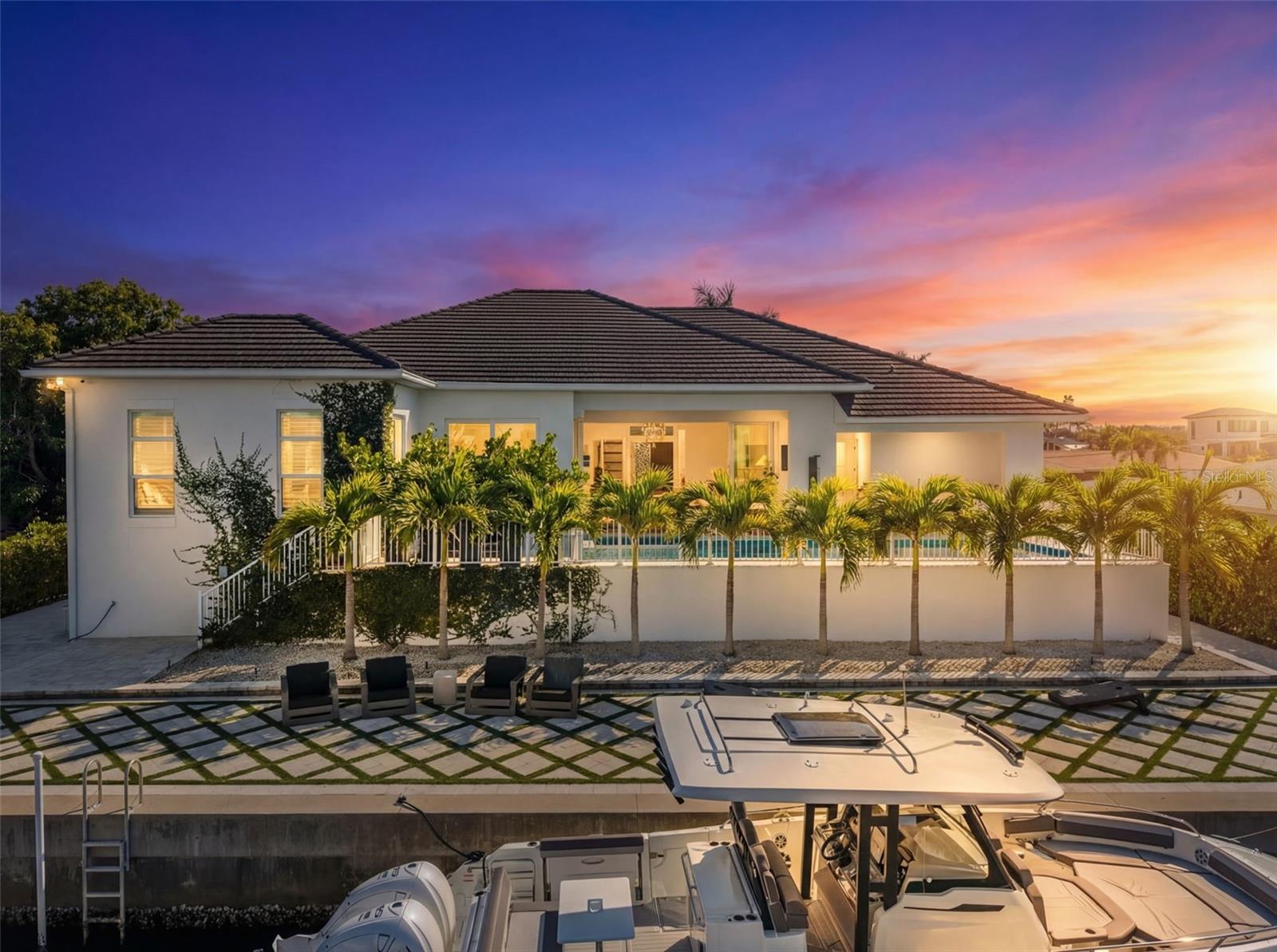 Perfectly positioned along the water, this exceptional residence offers a refined coastal lifestyle just moments from Siesta Key. Tucked away on a quiet street, the contemporary home enjoys southern exposure and approximately 100 feet of canal frontage with direct access to Sarasota Bay.

Designed for both entertaining and everyday living, the open-concept interior features soaring ceilings exceeding 14 feet and expansive walls of impact-rated pocketing glass. When opened, the living areas flow seamlessly to a covered outdoor lounge, resort-style pool and spa, and a fully equipped outdoor kitchen, creating effortless indoor-outdoor living.

The primary suite is privately located on the east side of the home and features oversized windows and glass sliders opening directly to the waterfront pool terrace, along with a custom walk-in closet and spa-inspired en-suite bath. On the west wing, two sun-filled guest bedrooms with walk-in closets share a beautifully appointed bathroom. A flexible bonus or media room serves as a fourth bedroom and includes an en-suite bath and walk-in closet.

Additional features include a dedicated study or den, a fully air-conditioned split three-car garage, and thoughtfully designed spaces that balance style and functionality. With direct boating access to the Intracoastal and no HOA restrictions, this property offers an ideal waterfront lifestyle.

Enjoy daily sunsets over the water and front-row views of Siesta Key’s Fourth of July fireworks—all from the comfort of your own home. Conveniently located minutes from Siesta Key Beach, Downtown Sarasota, and premier dining, shopping, and cultural destinations—including The Bay Park, Selby Gardens, and the Van Wezel Performing Arts Hall—this home presents a rare opportunity to enjoy contemporary design, privacy, and boating access in a sought-after coastal setting.