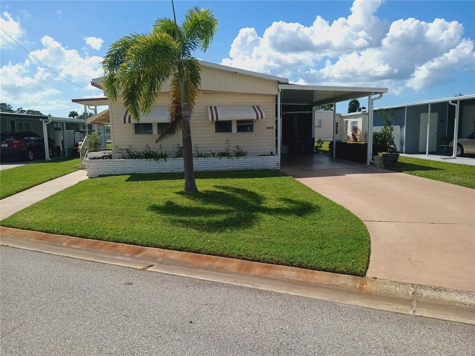 This fully furnished residence comprises two bedrooms and two bathrooms across 1,060 square feet. Notable features include spacious bedrooms, built-in dining room cabinetry, a recently installed TPO roof and carport, durable vinyl siding, an upgraded electrical box, a covered laundry area, and a large screened-in sitting area. Tri-par Estates offers amenities such as a year-round heated/cooled pool, spa, tiki hut, pickleball, fitness center, shuffleboard, miniature golf, horseshoes, game rooms, plus arts and crafts classes. The clubhouse hosts frequent social events. Conveniently located near downtown Sarasota, World-renowned beaches including Siesta Key and Lido Key are only a short drive away for leisure and relaxation, marinas, shopping, dining, museums, and the airport. Land rights are included with an annual $1,648 fee in your property taxes—no direct HOA fees. The community is golf cart-friendly and offers optional RV/boat storage.