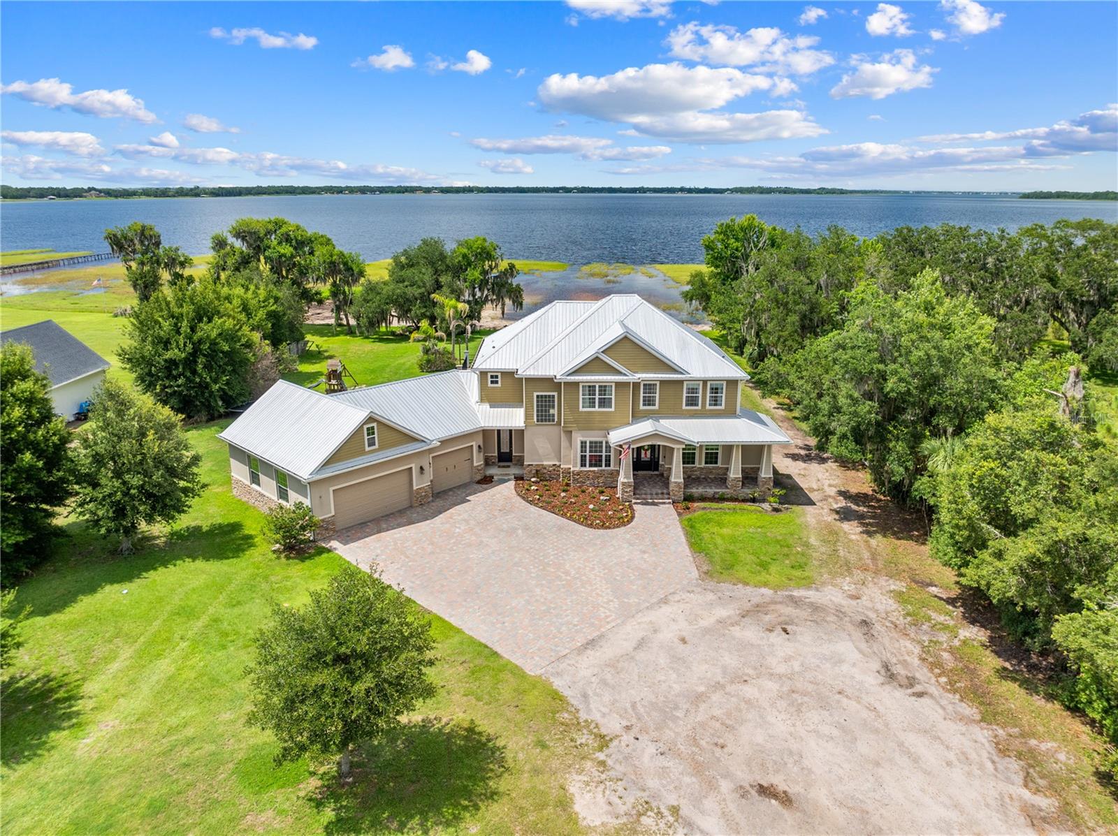 LAKE HOUSE on 4.22 private acres along the shores of Alligator Lake — with direct access to a coveted chain of lakes — this stunning 3,350 sq ft custom-built home delivers the lakefront lifestyle you've been waiting for. Thoughtfully designed across 4 bedrooms and 4.5 bathrooms, every detail speaks to quality craftsmanship, from the striking stone exterior and paver driveway to the soaring high ceilings, open floor plan, and elegant electric fireplace with custom wood surround.
The chef's kitchen impresses with marble countertops, rich wood cabinetry, a walk-in pantry, and stainless steel appliances — flowing seamlessly into the walk-in dining room, ideal for hosting. The master suite is a true retreat, offering a private glass balcony with sweeping lake views, a spa-like garden tub, and a generous walk-in closet. Outside, the heated pool and spa sit within a beautifully fenced paver patio and deck — perfect for entertaining or unwinding as the sun sets over the water.
Built to last with a durable metal roof, wood tile and carpet throughout, the property also features a three-car garage, a 40x60 block shop with upstairs office space, and a 40x60 pole barn with concrete — offering unmatched versatility for work, hobbies, or storage. This is rare lakefront living with room to breathe, built to impress. Inside laundry room and pool bath close by.