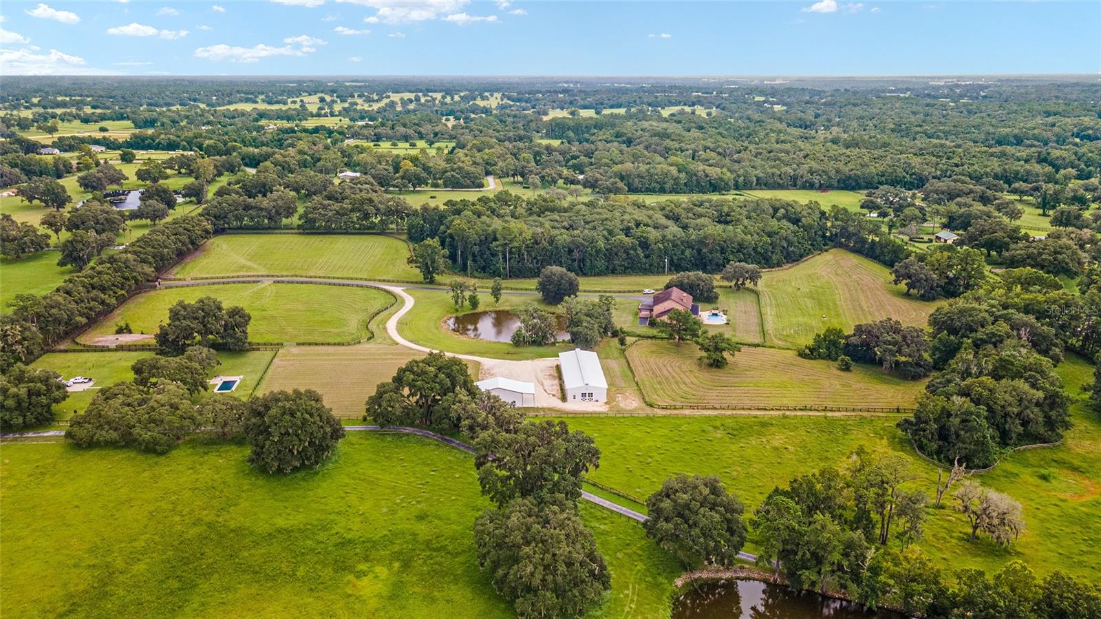THIS IS AN AMAZING NEW PRICE FOR THIS PROPERTY!! 
Possible Owner Financing*
Welcome to this 25+acre Equestrian Estate off the end of Millionaire's Row in Marion County's Horse Capital of the World. The 11 stall center aisle block barn is ready for your show horses with new paint, new stall doors, new beautiful barn doors with matching stall window shutters and all new rubber pavers. There's an inside wash stall, grooming stall, new half bath, new shower, new septic, tackroom, feed room and office with new tongue and groove ceilings. New barn driveway is shared with a brand new 30x50 shop with roll up doors, great for storing your tractor, trailer, jumps, hay, etc. There are a few huge pastures with lush grass, two auto waterers, a run in shed and plenty of room to add an arena. Across the pond with fountain is the 5,800 sq ft two story brick residence with 5 bedrooms, 4 full and 2 half baths, with first floor primary bedroom. A grand entrance with open foyer  and wooden staircase. First floor primary with two walk in closets with built ins, soaking tub, large shower and his and her vanities. A chef's kitchen with granite countertops, two walk in pantries, eat in kitchen, island and bar seating. Huge lanai accessed through multiple rooms by french doors looks out on the saltwater pool with water feature and solar heating. This is a beautifully constructed home with high ceilings, thick intricate crown molding and ceiling medallions, textured walls and a stone fireplace. A truly elegant home and peaceful setting surrounded by horse farms. Less than 10 minutes to the WEC Jockey Club, 15 minutes to HITS and 20 minutes to the famous World Equestrian Center. This property sits in the highly desired NW quadrant and has so much to offer.