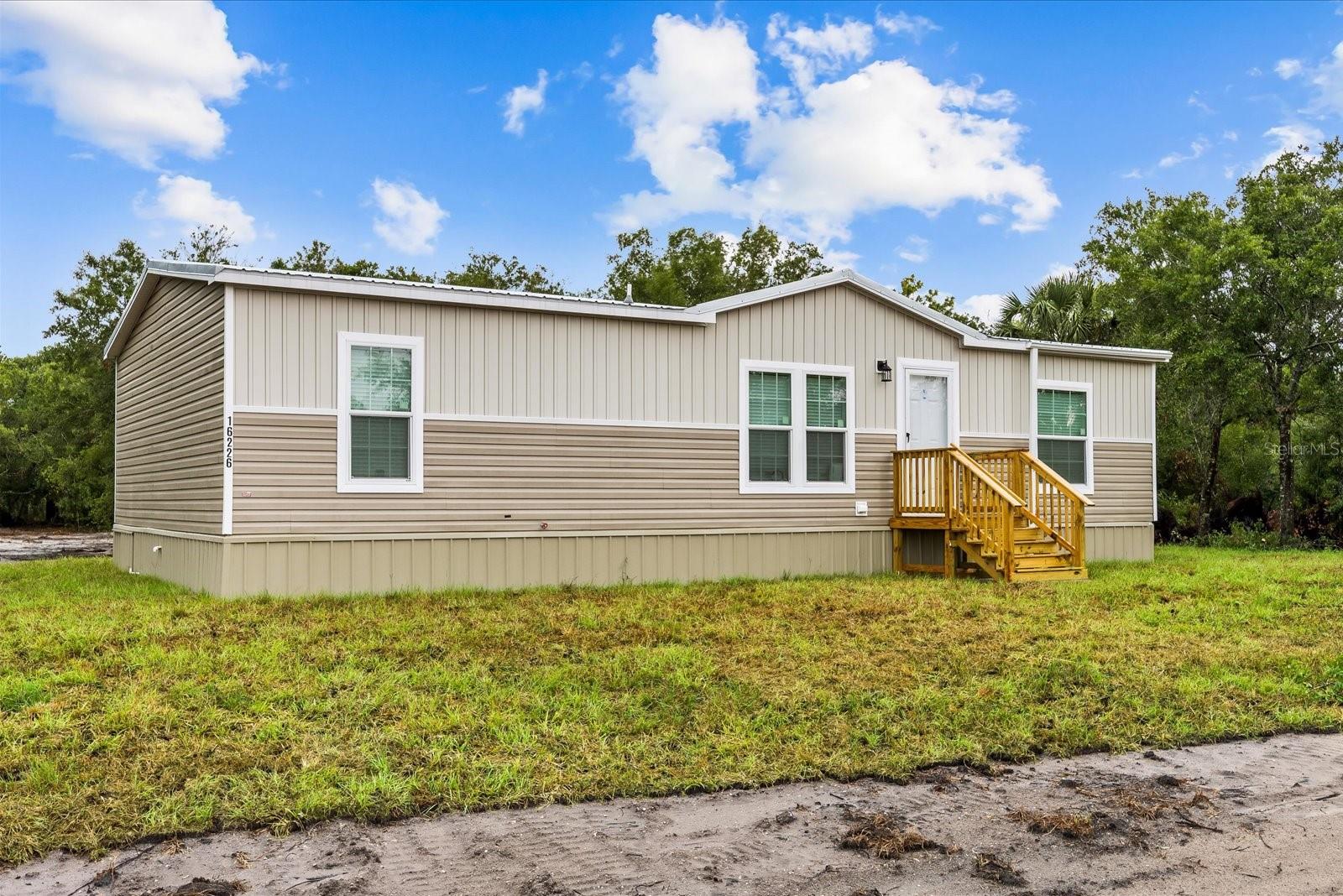 Don't miss the opportunity to own this stunning, brand-new ScotBilt Legend Series home located in the desirable Viking/Prairie community of Okeechobee. Offering metal roof, 3 bedrooms, 2 bathrooms, and 1,248 square feet of living space, this beautifully upgraded energy-star certified home sits on a private 1.25-acre lot shaded by mature oak trees, providing the perfect blend of comfort, privacy, and country living.
Designed with an open split-bedroom floor plan, this home features a spacious living area, separate dining space, and an impressive kitchen complete with a large island, 42-inch upper shaker-style cabinets, tile backsplash, driftwood pendant lighting, stainless steel appliances, and abundant storage. The primary suite offers a relaxing retreat with dual vanities, a walk-in shower, a separate freestanding soaking tub, and a spacious walk-in closet. Two guest bedrooms are located on the opposite side of the home and share a full guest bathroom.
Premium upgrades throughout include finished drywall, luxury linoleum flooring throughout, craftsman-style baseboards & crown molding, upgraded lighting and ceiling fan package, interior laundry room, and a striking two-tone Coastal Craftsman exterior featuring horizontal and vertical board-and-batten siding, and a durable metal roof.
This move-in-ready home comes complete with a well, septic system, central air conditioning, water filtration system, powder coated metal skirting with lifetime warranty, steps, and a newly constructed pond. The expansive 1.25-acre property offers endless possibilities with plenty of room for animals, recreational vehicles, boats, RVs, or future additions such as a barn, workshop, garage, or pool.
Conveniently located just minutes from the main road, you'll enjoy easy access to Lake Okeechobee, the airport, shopping, dining, schools, and everything Okeechobee has to offer.
Schedule your private showing today and experience the quality, craftsmanship, and value this exceptional new home has to offer. Seller also has additional move-in-ready homes, homes currently under construction with 30-45 day completion timelines, and land available within the community.