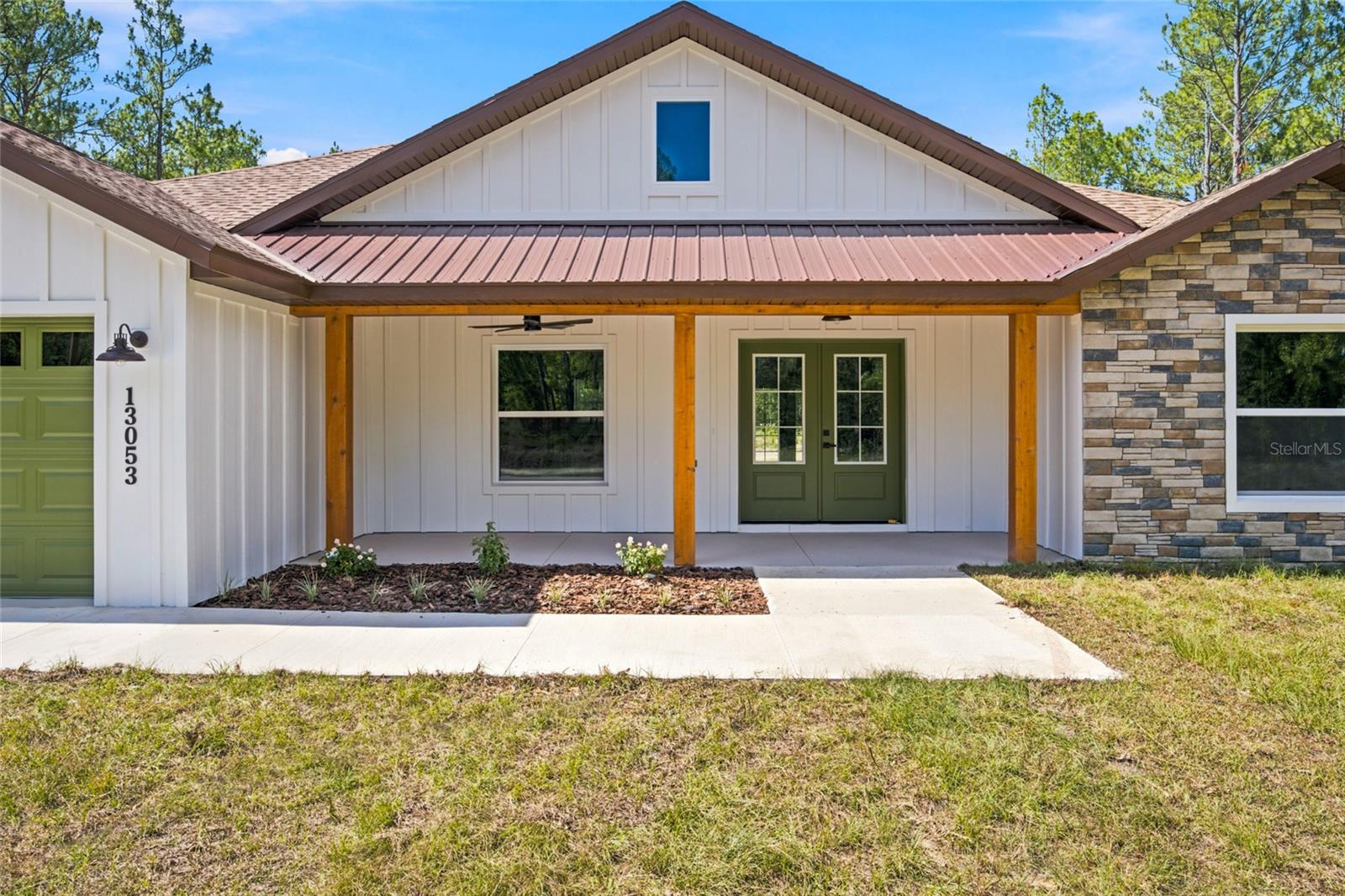 Welcome to this beautifully crafted farmhouse-style retreat situated on 1.19 fully cleared acres, offering the perfect blend of rustic charm and modern comfort. With 1,751 sq ft of air-conditioned space and 2,475 total sq ft, this home boasts inviting curb appeal, featuring a spacious front porch and a relaxing lanai, perfect for enjoying peaceful country living. Step inside to a warm farmhouse-inspired interior with rustic aesthetics throughout. The heart of the home is the expansive open-concept kitchen, thoughtfully designed for both functionality and entertaining. Enjoy upgraded wood cabinetry, a stylish farmhouse sink, upgraded appliances, built-in microwave conveniently located in the island, a hood vent for enhanced cooking ventilation, and a convenient pot filler above the stove. The spacious living area features a built-in electric fireplace beneath the entertainment center space, creating a cozy focal point for gatherings and relaxing evenings. The oversized primary suite offers a private retreat with a large walk-in closet thoughtfully located within the bathroom to maximize wall space in the bedroom. The luxurious primary bath also includes dual his-and-her sinks for added convenience and comfort. With its open layout, upgraded finishes, charming farmhouse exterior, and generous cleared acreage, this property offers the perfect balance of style, space, and functionality.