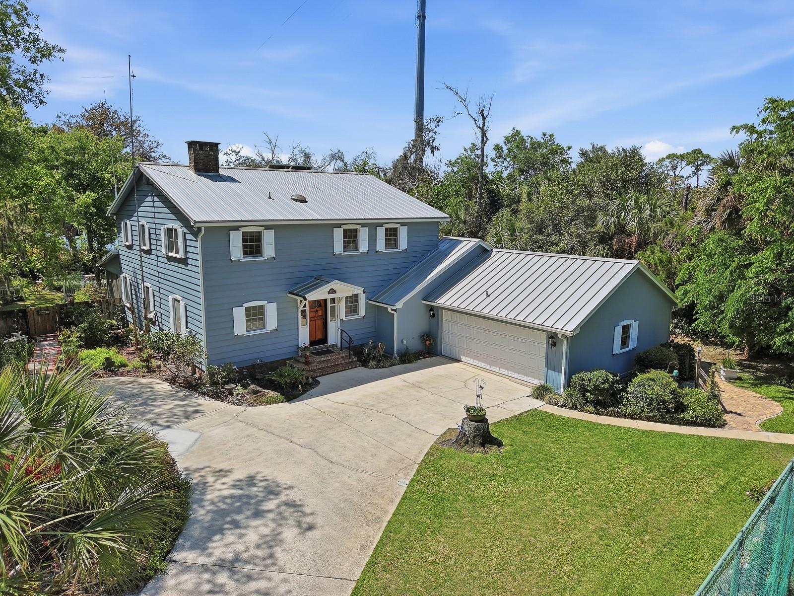 This extraordinary Craftsman-style estate offers almost 4,000 square feet of living space and stands as a rare, authentic expression of timeless Florida design. From the moment you arrive, the home’s architectural integrity and enduring charm are unmistakable—every detail thoughtfully curated, every inch rich with character. Set on a sprawling 1.34-acre lot, the property offers 112 feet of direct frontage on Spruce Creek, delivering a true waterfront lifestyle. Enjoy seamless access to the water with a private dock, boathouse, and boat lift—perfect for boating enthusiasts and nature lovers alike. Inside, warm wood accents, and natural textures create an inviting, refined atmosphere throughout. The home features four spacious bedrooms, three and a half bathrooms, and a dedicated office, perfectly suited for both everyday living and remote work. Two wood-burning fireplaces—one anchoring the main living room and another in the private primary suite, both adding a sense of comfort and classic elegance. A standout feature is the expansive great room, completely flooded in natural light and thoughtfully designed with flexibility in mind. Complete with a private entrance, full bathroom with clawfoot tub, and kitchen, this space can easily function as an in-law suite, guest quarters, or private retreat. Outdoors, the grounds are nothing short of enchanting- The pool area has been reimagined as a serene koi pond, complete with a fountain, stacked stone and surrounded by lush, native Florida plants- while still retaining the potential for reconversion to a traditional pool. Adding to the estate’s resort-style appeal is a private tennis court, offering the perfect space for recreation, exercise, or entertaining guests in a picturesque setting. The backyard continues to impress with its natural landscaping, with every square inch thoughtfully designed to celebrate Florida’s native beauty while creating a peaceful, private sanctuary. All major systems have been upgraded, including a commercial-grade metal roof that ensures durability and decades of longevity, while three separate air conditioning units and newer water heater provide comfort and efficiency throughout the home. 
This is more than a residence—it’s a timeless retreat where craftsmanship, nature, classic Florida design and pride of ownership shine throughout and come together in perfect harmony.