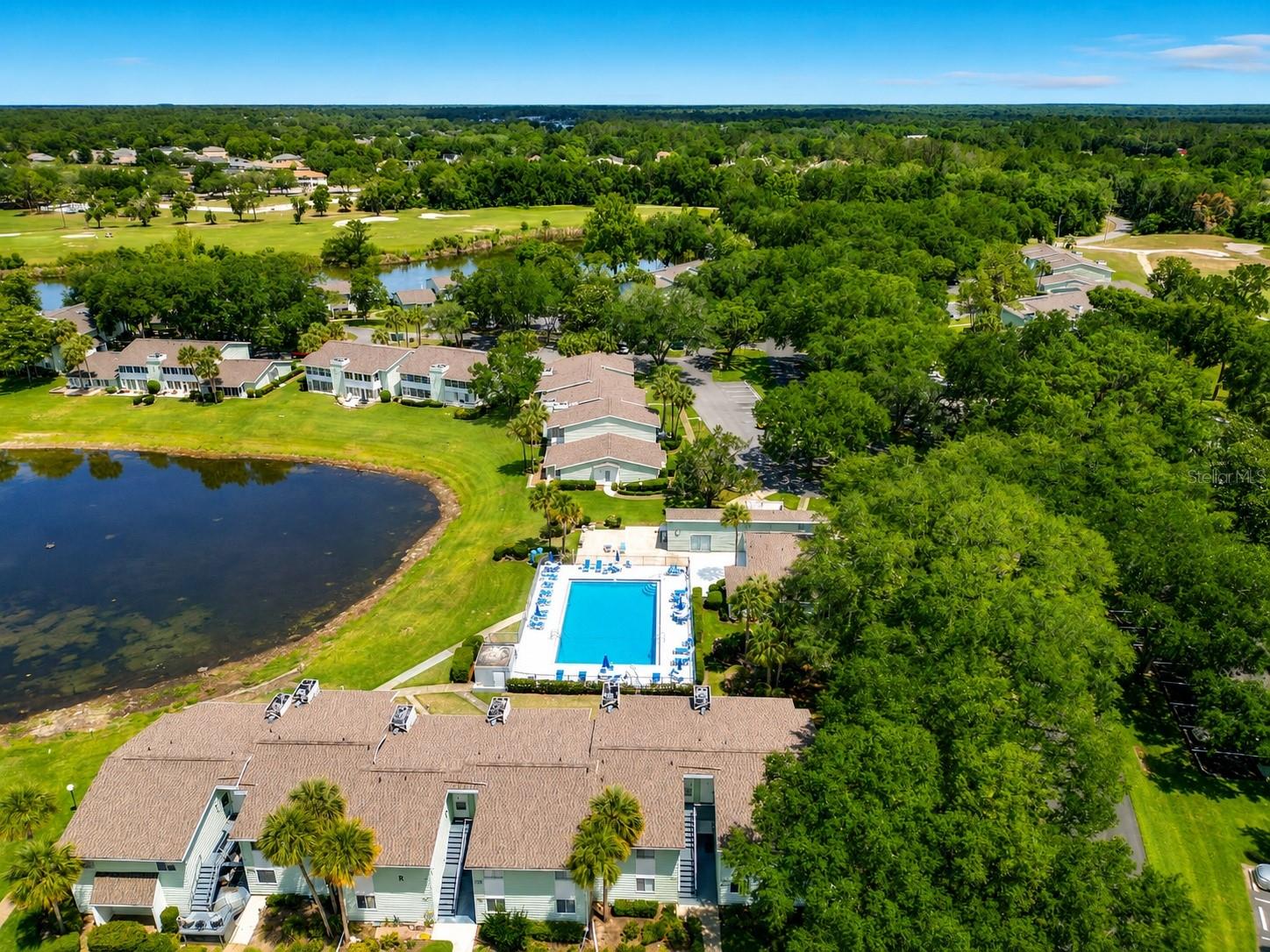 Amazing price!!! Overlooks the pool! Welcome to Live Oak Village, a peaceful 55+ community nestled beneath the shade of Ocala’s beautiful oak trees, and bordering The Country Club of Silver Springs Shores golf course. This unfurnished two-bedroom, one-and-a-half-bath condo features newly installed flooring throughout and is move-in ready for its next owner. Residents enjoy a low-maintenance lifestyle with HOA fees that include basic cable, exterior insurance, trash service, upkeep of the building and common grounds, plus access to the community clubhouse and swimming pool, just steps away from the unit. Conveniently located near shopping, pharmacies, dining, and scenic walking and hiking trails, this community offers both comfort and convenience. The enclosed Florida room overlooks the community pool, clubhouse, and picturesque Lake Sparkle, creating a serene space to unwind and enjoy the view.