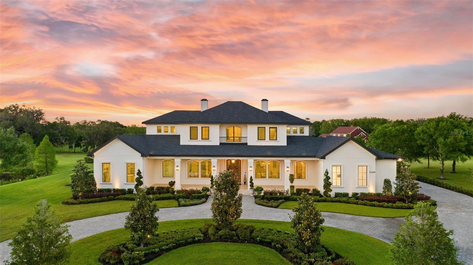 Upon first glance, the impeccable attention to detail, exquisite finishes, and a joy of symmetry are immediately apparent, setting a theme of enjoyment in this magnificent home. *Use 10400 Oak Canopy Drive for the gate.  Spanning 7,406  square feet of sheer entertaining perfection, this residence is situated pondside on two scenic acres within the ultra-exclusive Stonelake Ranch. The home features five bedrooms, five full bathrooms, two half bathrooms, an office, and a plethora of special touches, making it standout. From the moment you approach, the use of premium materials such as fine wood, metal, and stone is evident. The estate is positioned on its acreage to maximize privacy and includes a fishing pond, extensive green space, and open backyard views.  A grand driveway of granite colored cobblestone cement pavers leads to the impressive custom smokewood doors, which are perfectly complemented by the tongue and groove ceiling of the expansive travertine front porch. Entering the home, you are met with soaring 24-foot ceilings and the elegant sight of a Midwestern-style oak and wrought iron staircase, setting the stage for the formal dining and living rooms. These areas are distinguished by a crafted stone gas fireplace and wide plank hardwood floors throughout. The heart of the home is the chef’s dream double island kitchen, fully equipped with top-of-the-line appliances and designed for both functionality and luxury. This includes Café Double French Wall Ovens, a 48" Sub-Zero refrigerator, and a 36" 6 burner grill, and dual Bosch dishwashers. The kitchen facilitates superb guest service with its island breakfast bar, breakfast nook, butler’s pantry with a 48-bottle Zephyr wine fridge, and a specialty nugget  ice maker.  The adjoining massive great room, with its exposed smokewood beams and stone-faced gas fireplace, seamlessly extends into the expansive screened lanai, pool, and outdoor kitchen, enhancing the indoor-outdoor living experience. Here pocketed sliding doors blur the lines between in and out offering all a picturesque view of sunset over the pond from poolside. The beautifully appointed and finished salt water pool is surrounded by a sea of light ivory French pavers and features a heated spa, customizable RGB lighting, and pool alarm.  The estate’s first-floor primary suite is a true sanctuary, featuring a breathtaking picture window view of the pond from the freestanding bathtub, luxurious dual vanities, a step-in shower, dressing lounge, private yoga room, and direct pool access. 
The first-floor secondary suite also spares no luxury, equipped with expansive dual vanities, a garden tub, and a step-in shower, ensuring comfort and style. Upstairs, additional guest rooms with ensuite bathrooms offer spectacular views and are complemented by a loft lounge overlooking the foyer and pool area. Completing this extraordinary home are a finely detailed office, a dual-functional mudroom/laundry room with a pet wash station, and a spacious four-car garage. Advanced features such as a 500-gallon private reserve propane tank, comprehensive security system, and potential for an elevator installation ensure both convenience and peace of mind. Community amenities like equestrian trails, a lakeside lodge, and various recreational courts add to the luxurious lifestyle.