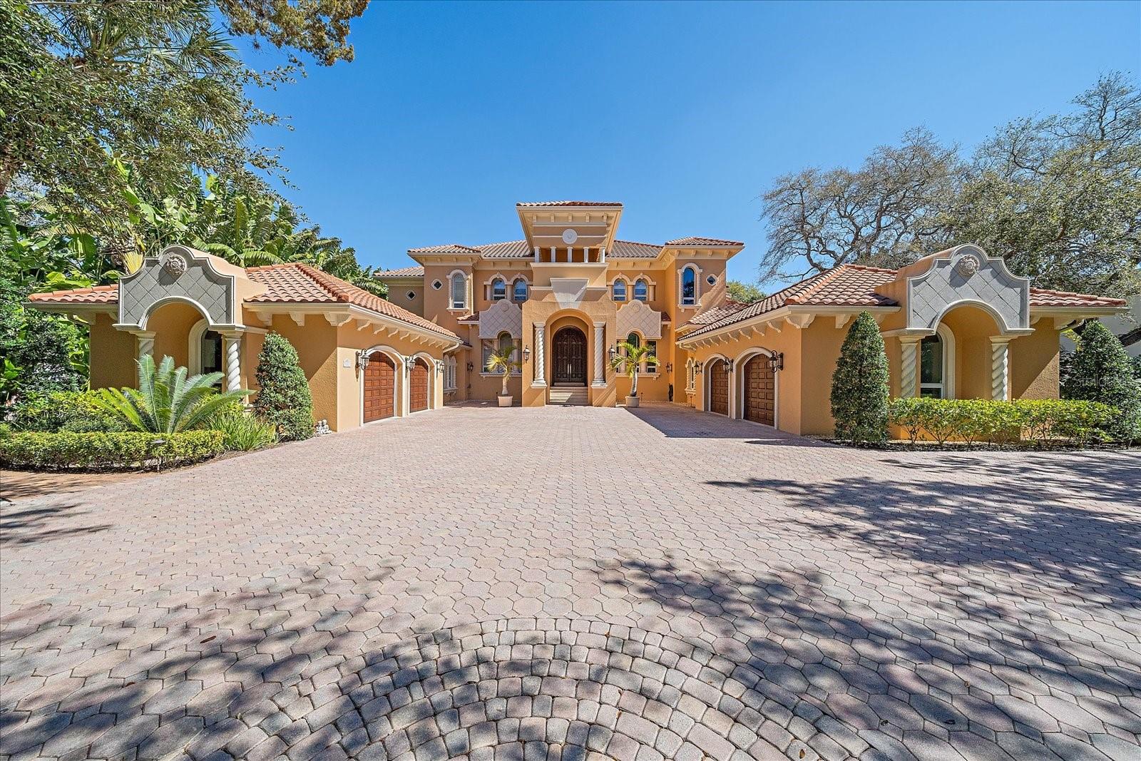 Experience elegance and waterfront luxury at 1321 Point Crisp Rd, Sarasota, FL – an exquisite 5-bedroom, 6.5-bathroom, 1.35 acre estate that harmoniously blends sophistication with the natural beauty including a beautiful garden on Sarasota Bay. Nestled on the prestigious Point Crisp enclave, this home spans over 6,572 sqft of opulent living space, offering panoramic bay views that encapsulate the essence of Florida’s coastal living. As you approach this magnificent home, the expanded paver driveway leads to a commodious 4-car garage, setting a regal tone. The entrance unveils a grand foyer graced with travertine tile, inviting you into a realm where every detail is meticulously crafted to perfection. The essence of luxury is palpable throughout, from the crown molding and tray ceilings that add depth and character to each room, to the farmhouse sink and breakfast bar that complement the bespoke kitchen. Equipped with a Viking gas cook-top and under-cabinet lighting, culinary adventures await. The kitchen unifies form and function with a custom wine room and wet bar, enhancing the home’s entertainment capabilities. Immerse yourself in the panoramic bay views from the great room, where wood-burning fireplace warmth meets cathedral ceilings grandeur, creating an ambience that is both majestic and inviting. The living room captivates with full open sliders, seamlessly blending indoor opulence with the tranquility of the outdoor patio. Here, overlooking the heated saltwater pool, luxury meets leisure in a setting that boasts rare yard space and a private dock with an electric boat lift. Each of the estate’s five bedrooms comes with its own en suite, ensuring privacy and comfort for family and guests alike. The primary bedroom is a haven of tranquility, offering enchanting bay views and outdoor living space that beckons for mornings spent in serenity. The luxury en suite bathroom, complete with a soaking tub, expanded shower, and double vanity, serves as a private spa for relaxation and rejuvenation. Not to be overlooked, the media room, equipped with surround sound, offers an immersive experience for movie nights and gatherings. Additionally, the home boasts office spaces on both the first and second floors, accommodating the needs of those who work from home or require a quiet study. Its strategic location not only presents breathtaking vistas but also places you within proximity to Sarasota’s renowned dining, shopping, and cultural offerings. The embodiment of luxury and leisure, this property promises a lifestyle that is both sumptuous and serene. This home is more than just a residence; it is a masterpiece of design and craftsmanship that offers an unparalleled lifestyle. With its rare yard space, in addition to the heated saltwater pool and private dock with an electric boat lift, leisure and luxury converge in an exquisite waterscape setting. Whether you are hosting gatherings, enjoying quiet moments by the pool, or setting sail from your private dock, this estate caters to every aspect of upscale living. In summary, 1321 Point Crisp Rd stands as a testament to luxury waterfront living. With panoramic bay views, high-value interior and exterior characteristics, and unparalleled amenities, this property is truly a rare gem in Sarasota’s prestigious landscape. Do not miss the opportunity to own this pinnacle of waterfront luxury.
