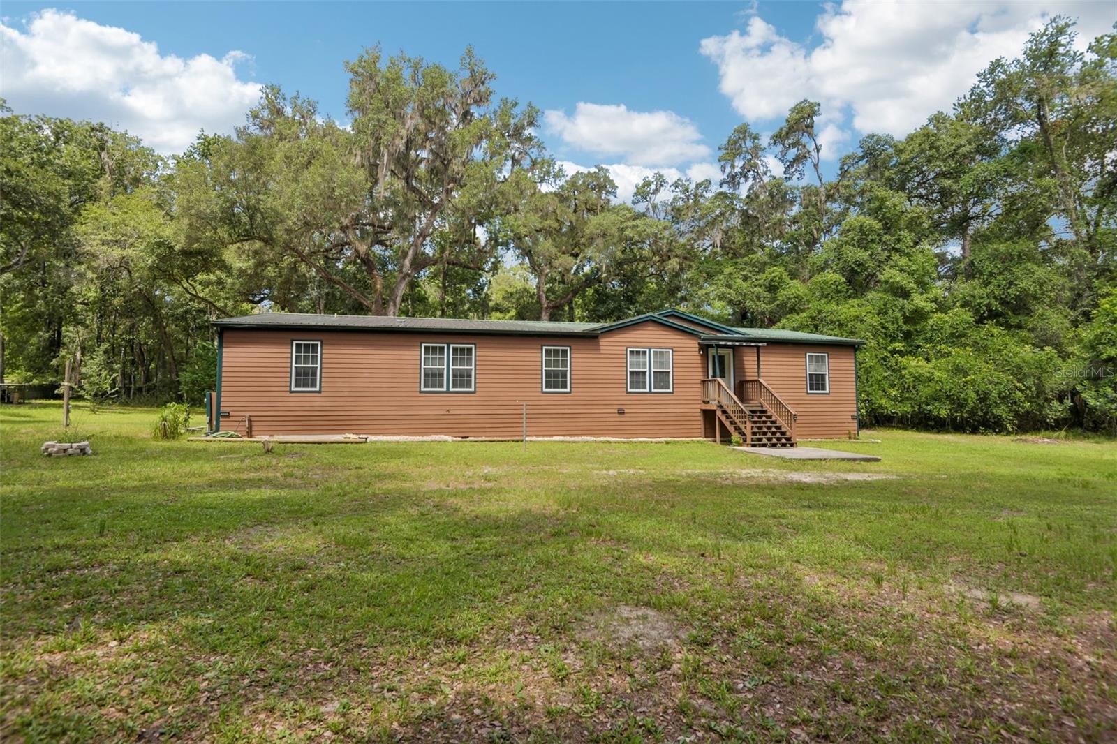 If you've been dreaming about owning land without giving up the convenience of town, **6221 Emerson Road** offers the best of both worlds. Nestled on **nearly 10 beautifully wooded acres**, this property provides the peace, privacy, and freedom that are becoming harder to find in today's market.

As you make your way down the driveway, you'll immediately notice the quiet setting. Surrounded by mature trees and natural Florida landscape, it feels like your own private retreat, yet you're only minutes from **historic Downtown Brooksville**, shopping, restaurants, medical facilities, schools, and everyday conveniences.

The home is a **spacious double-wide manufactured home built in 2007**, offering comfortable living with plenty of room to spread out. Whether you're looking for a full-time residence, a weekend getaway, or a property with room to expand, this home provides an excellent foundation.

One of the standout features is the **oversized detached metal garage**, offering exceptional space for vehicles, boats, RVs, equipment, hobbies, or a workshop. Finding a property with this much storage and workspace is rare, making it ideal for mechanics, contractors, outdoor enthusiasts, or anyone needing extra room.

The nearly **10-acre wooded parcel** offers endless possibilities. Create ATV trails, enjoy hiking on your own property, build additional outdoor living spaces, keep recreational vehicles, or simply appreciate the privacy and abundant wildlife. The natural setting creates a peaceful atmosphere while still leaving plenty of usable land for future plans.

Location is another major advantage. Brooksville continues to grow while maintaining its small-town charm. You'll be just minutes from **Downtown Brooksville**, local parks, restaurants, shopping, medical facilities, and within easy driving distance of the **Suncoast Parkway**, providing convenient access to Tampa, the Gulf Coast, and surrounding communities.

Properties offering **nearly 10 acres**, a **well-maintained home**, a **large detached metal garage**, and this level of privacy—while still being close to town—are becoming increasingly difficult to find. Whether you're looking for space to enjoy the outdoors, room for your toys and equipment, or simply a quiet place to call home, 6221 Emerson Road offers a unique opportunity to enjoy country living without sacrificing convenience.