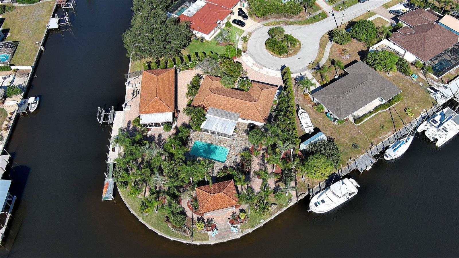 One or more photo(s) has been virtually staged. Waterfront Estate Living. A Rare Waterfront Oasis in Port Charlotte only minutes from the Charlotte Harbor, Peace River and Boca Grande Pass offering some of best boating and fishing on the Suncoast.  Discover a truly one-of-a-kind waterfront enclave on deep sailboat water with direct Gulf of America access. This exceptional property combines luxury, privacy, and coastal charm in one seamless package.  Truly a Boaters dream. The dock accommodates vessels up to 70 feet, complete with a 10,000 lb. lift, twin Davits and a floating dock.  The main residence was completely renovated and offers approximately 2,600 square feet of air-conditioned living space, showcasing elegant travertine flooring and a spacious open-concept design. It features two full ensuite primary bedrooms, plus a flex room ideal as a third bedroom, office, or den. The main home includes a two-car garage, two and a half baths, and a large, air-conditioned Florida room perfect for year-round enjoyment. Thoughtful details add warmth and sophistication, while hurricane-impact windows and sliding doors provide peace of mind. The separate 864 square feet guest cottage enhances the property’s versatility, complete with an additional three-car garage with a half bath. The cottage has one bedroom, one full bath, and a modern kitchen featuring custom Italian porcelain flooring throughout, plus an in-unit washer and dryer. Outside, the estate is surrounded by lush tropical landscaping, massive coral boulders, flowering gardens, and inviting patios and walkways, creating the perfect backdrop for both quiet relaxation and grand entertaining. Over 10,000 square feet of pavers accent the property, including a large front parking area, a private courtyard, and surrounded with a 6-foot privacy wall with custom ornamental gates for added security and elegance.  The resort-style pool area features a stunning 32’ x 16’ pool surrounded by 2,500 square feet of North Carolina flagstone decking, and a 28’ x 16’ pavilion ideal for outdoor entertaining, observing  spectacular Florida Sunsets, dolphin, ospreys and various fish playing in your backyard.  Park your luxury Motorcoach on the property with full hookups.  For boating enthusiasts, this is paradise. If you’re searching for the perfect coastal retreat to moor your sailboat, yacht or simply enjoy luxurious waterfront living, this home is the ultimate find. Schedule your private showing today and experience this extraordinary property firsthand.