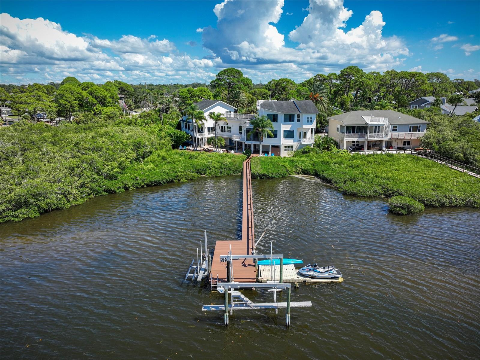 Discover the pinnacle of waterfront living in this extraordinary residence offering 5469SF of thoughtfully designed space. With 6 bedrooms, 5.5 bathrooms, and two luxurious primary suites, this home is perfectly tailored for multi-generational living. Nearly every room captures breathtaking water views, blending elegance and serenity at every turn.

Designed with versatility in mind, the home features two distinct wings joined by a remarkable custom, high-tech bookshelf that opens by key fob. Closed, it’s a sophisticated architectural statement; open, it reveals the West Wing with a formal living room, library/guest suite, large private office with extraordinary water views, elevator, and a dramatic staircase leading to the second primary suite. This third floor primary suite with elevator access offers westward water views,  a fully remodeled spa bath with soaking tub, walk-in steam shower, and dual vanities and dual walk in closets.

The East Wing is equally impressive, offering a fully renovated open-concept kitchen with custom two-toned cabinetry, expansive marble counters, Wolf appliances, double ovens, induction cooktop, and wine fridge. Expansive porcelain plank flooring, wood accents, custom iron railings, and designer chandeliers elevate the home’s style. Upstairs, three additional bedrooms—two with balcony access—offer sweeping water views and a beautifully renovated guest bath.

Outdoors, the lifestyle continues with ~2,200 sq. ft. of composite decking, a sparkling pool and spa, updated landscaping, and a new gas-heater for the hot tub. Boaters will appreciate the newly update composite dock with 13,000 lb. lift, floating dock for jet skis, and deep-water access to the Gulf. The  At day’s end, ascend to the rooftop deck for panoramic sunsets that capture the essence of Florida’s waterfront lifestyle.

Additional features include a 3-car garage, elevator servicing all floors, game room with pool bath, and numerous recent updates: New boat lift Motors (2025) New Composite Dock (2025) New AC Compressor and air handler (2024) new hot water heater (2024), front window replacement (2024), upgraded flooring, renovated bathrooms throughout the home,  custom staircase steps, new outdoor shower and even a sand pit fire-pit for relaxed evenings outdoors. Top this off with a new roof which will be replaced PRIOR to Closing!

Perfectly situated along scenic Sutherland Bayou and adjacent to Pop Stansel Waterfront Park, this home is zoned for top-rated schools including Ozona Elementary and Palm Harbor University High School. No leasing restrictions or HOA restrictions in place! AirBNB investors welcome!

Every detail has been carefully considered to deliver luxury, comfort, and a true waterfront lifestyle. Don’t miss your chance to experience this one-of-a-kind property—schedule your private tour today