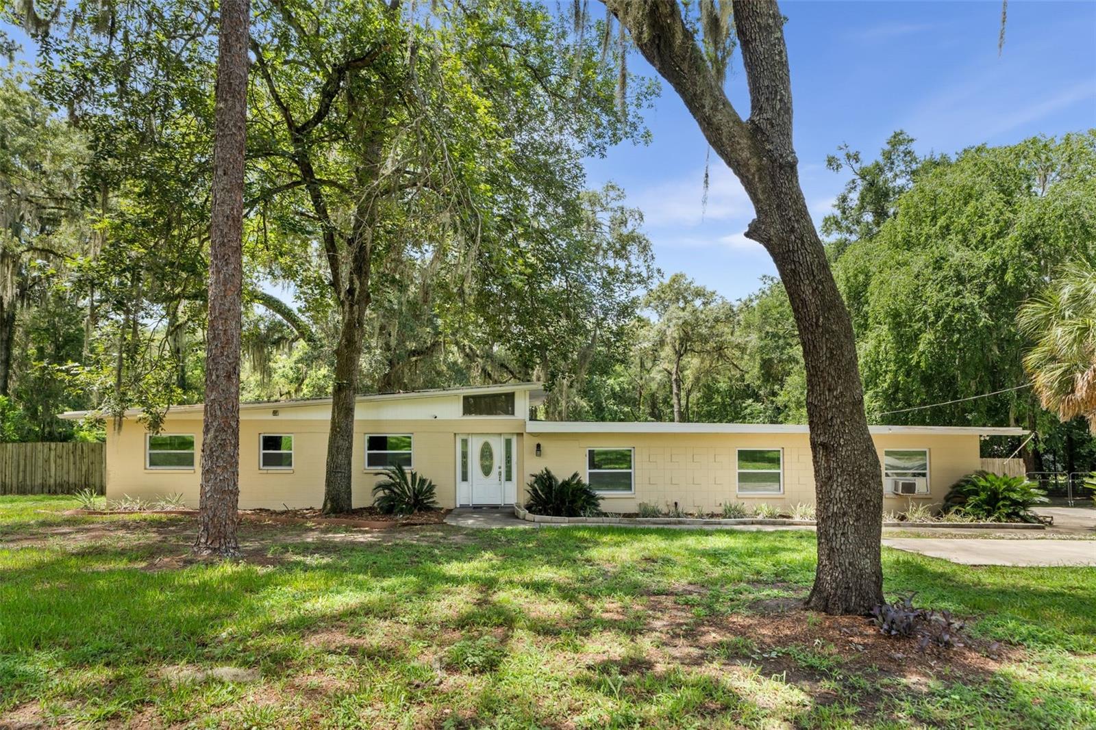 Situated on 1.33 acres in Namora Estates, this 3-bedroom, 2-bathroom Modern ranch style offers over 2,000 square feet of heated living space filled with natural light and a peaceful setting just minutes from Gainesville. The kitchen includes stainless steel appliances, ample cabinetry, and a breakfast bar overlooking the main living space with a brick fireplace. The primary suite features a walk-in closet and private bath with a double vanity and walk-in shower. Washer and dryer are included, along with a whole-house water softener and filtration system. Outside, enjoy the covered patio and expansive backyard surrounded by mature trees, with plenty of room for gardening, pets, and outdoor activities. A storage shed and attached two-car garage provide additional storage and functionality. Conveniently located off SW 24th Avenue, this home provides easy access to shopping, dining, I-75, the University of Florida, and medical facilities, while still offering the feel of a more rural setting.