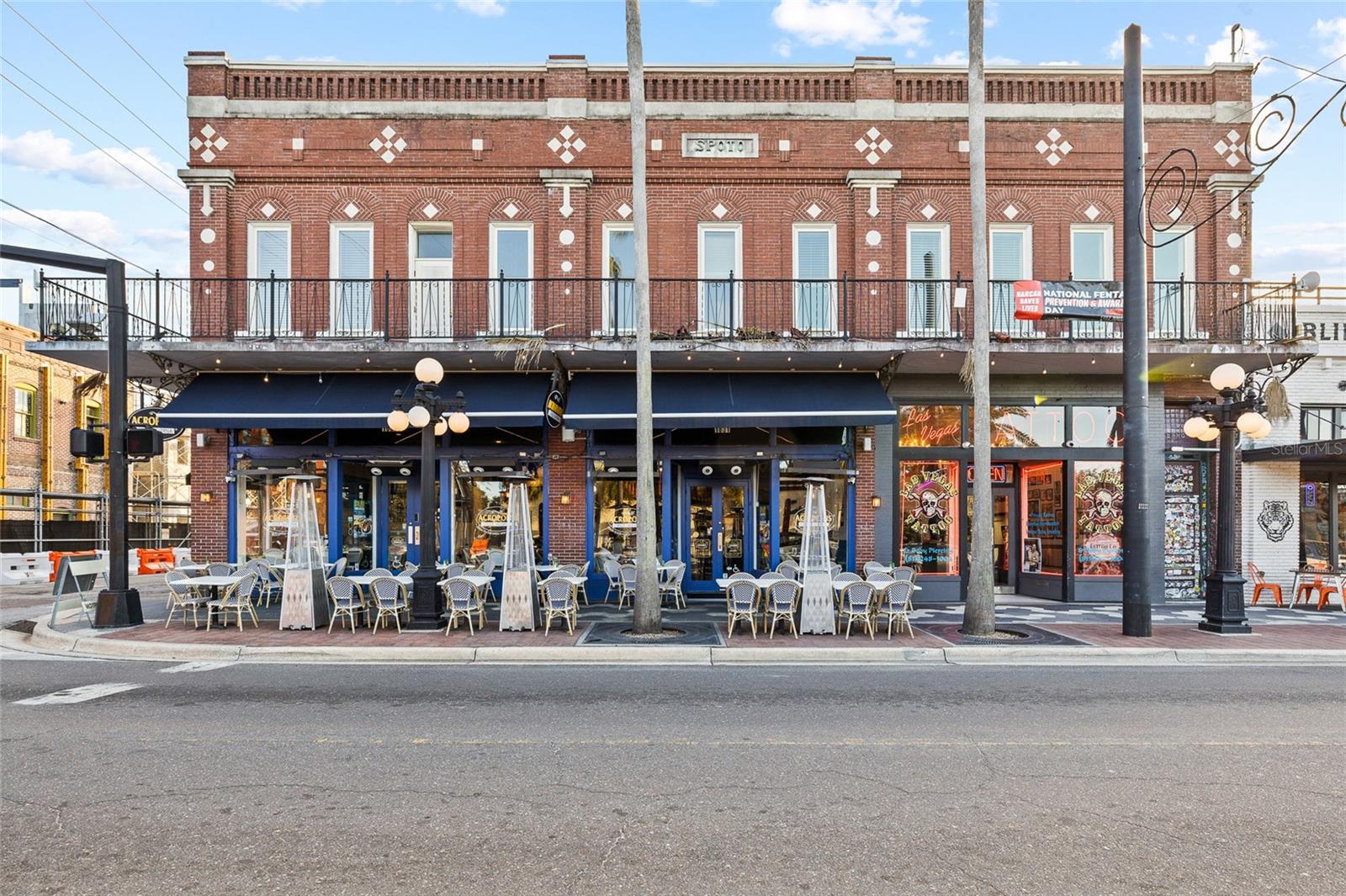 Occupying a prime corner on E 7th Avenue — Ybor City's main commercial corridor — this landmark two-story red
brick building delivers irreplaceable character alongside flexible space for retail, restaurant, and professional office
tenants. Built in the late 19th century, the property features ornate facade detailing, a wrought iron balcony, and a
stunning upper-floor suite with exposed brick, hardwood floors, skylights, and a signature executive boardroom.