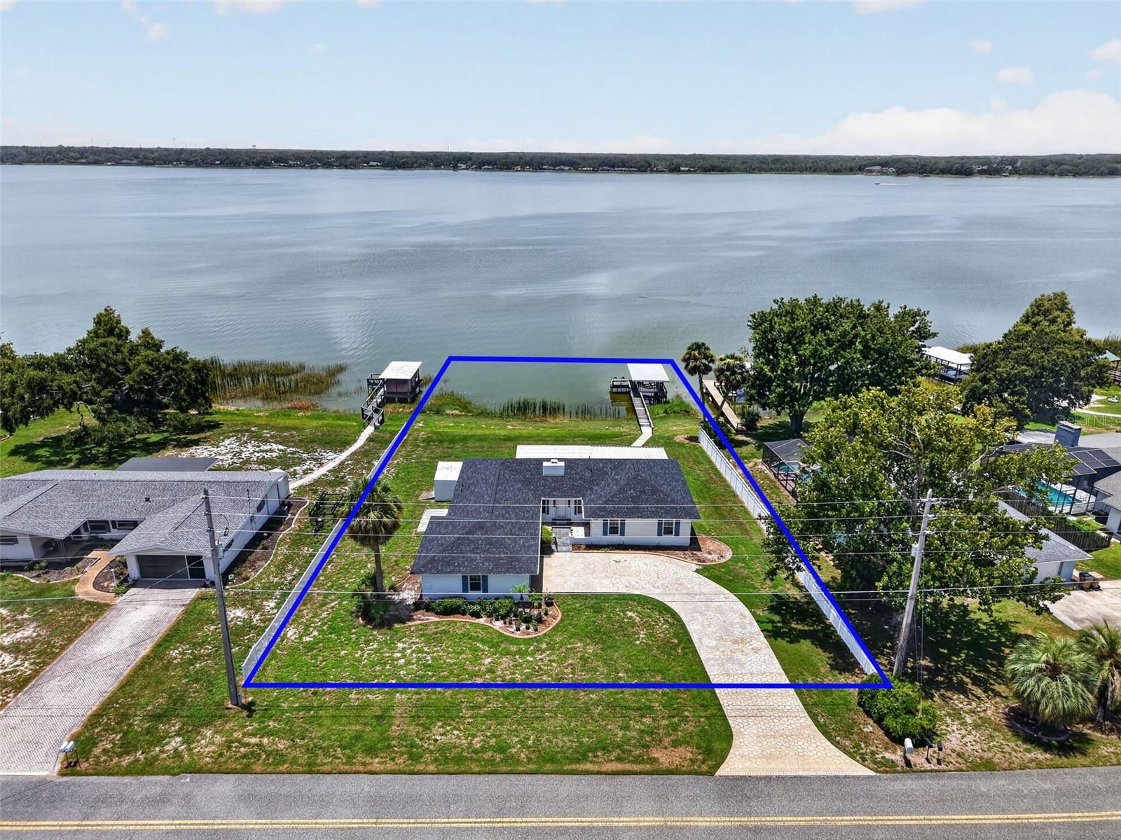 Virtually Staged. ENJOY BREATHTAKING LAKEFRONT LIVING on LAKE GRIFFIN, part of Florida's renowned HARRIS CHAIN of LAKES, in this BLOCK and STUCCO 3-bedroom, 2-bath home offering 122 feet of DIRECT WATERFRONT on just under ONE-HALF ACRE! BRAND NEW ROOF(6/26)!     Whether you enjoy championship bass fishing, boating, water skiing, jet skiing, or weekend adventures by boat all the way to Jacksonville via the St. Johns River, this EXCEPTIONAL PROPERTY places it all at your doorstep! Spend your days exploring the Chain of Lakes, then dock at one of the area's waterfront restaurants for dining, entertainment, and shopping before returning home to your own PRIVATE WATERFRONT RETREAT! A decorative stone-pattern driveway, tropical curbed landscaping, and a charming GATED COURTYARD with slate flooring and stone-edges create a warm and inviting first impression. Enter in through a double side-lit door that opens to a GENEROUS 5’x21’ foyer featuring elegant SLATE flooring and a convenient coat closet. Beyond, the OPEN-CONCEPT living and dining areas are perfectly positioned to capture SPECTACULAR LAKE VIEWS! The EXPANSIVE living room is anchored by a dramatic floor-to-ceiling COQUINA wood-burning FIREPLACE with a wood mantel, creating a stunning focal point! The dining room is equally impressive, with DOUBLE oversized windows showcasing UNINTERRUPTED LAKE VISTAS that create the perfect backdrop for everyday meals and special occasions, while the adjoining kitchen features LAMINATE flooring, cocoa cabinetry, and a wall oven. From the living room, sliding glass doors frame PANORAMIC views of Lake Griffin while providing seamless access to the 21'x17' GLASS-ENCLOSED LANAI, an ideal space for year-round entertaining or simply relaxing while watching stunning sunsets over the water! Just beyond, the 24’x14' COVERED PORCH extends your outdoor living space and leads directly to the PRIVATE DOCK and COVERED BOAT LIFT with a lakeside bench and fishing chairs, making it effortless to enjoy everything waterfront living has to offer! Back inside, the spacious primary suite features LAMINATE flooring, LARGE picture windows overlooking the lake, and a GENEROUS WALK-IN closet. Its ensuite bath offers TILE flooring, custom COQUINA tub, and a corner WALK-IN tiled shower. Bedrooms two and three each feature LAMINATE flooring, two windows, and built-in closets. There’s also a FAMILY/BONUS ROOM that provides even more space for entertaining, relaxing, or creating the perfect flex space to fit your lifestyle. Completing the package is a TWO-CAR GARAGE with a sliding screen door, built-in workbench, dedicated laundry nook, utility sink, shelving, attic access with stairs, and PLENTY of room for parking and storage! For added convenience, there are also TWO exterior STORAGE SHEDS and electric and septic HOOKUP CONNECTIONS for an RV! With generous living spaces, incredible indoor-outdoor flow, private boating amenities, and endless opportunities for recreation on one of Central Florida's premier lake systems, this INCREDIBLE WATERFRONT PROPERTY offers the perfect combination of comfort, beauty, and the ultimate Florida lifestyle! DON’T MISS YOUR OPPORTUNITY TO MAKE IT YOUR OWN! PLEASE WATCH OUR WALKTHROUGH VIDEO and CALL TODAY to schedule your private showing or virtual tour!