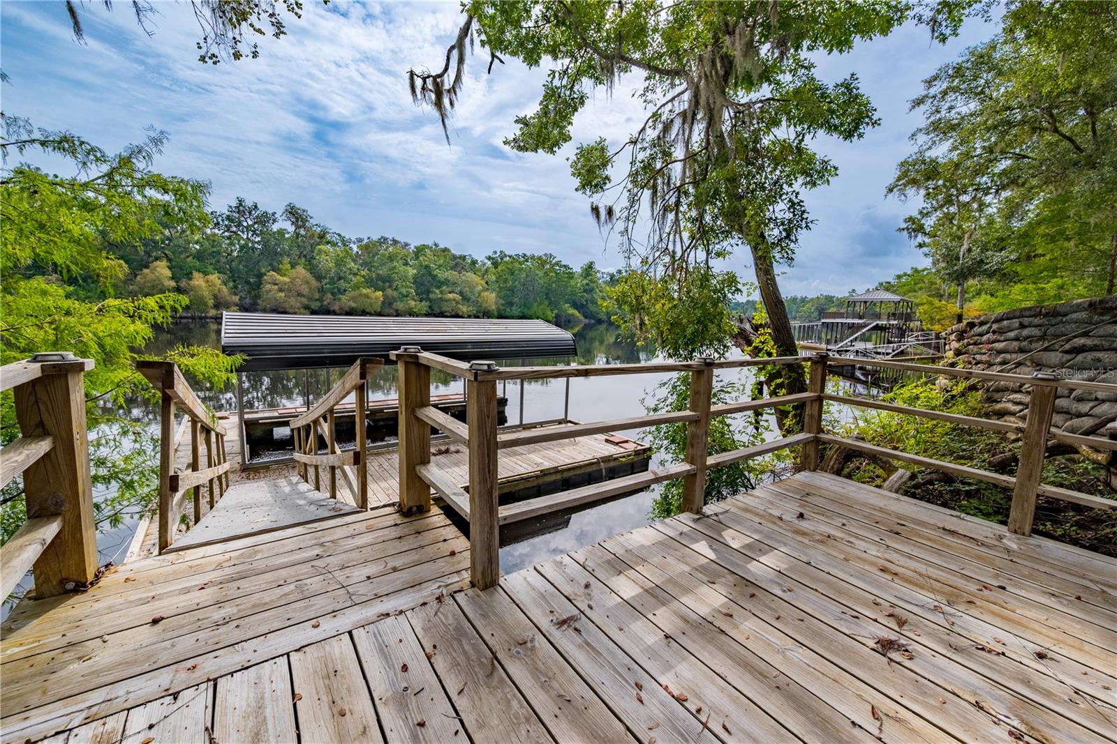 Suwannee Riverfront Home & Airbnb Retreat with Private Dock! This fully furnished waterfront home on the Suwannee River offers the perfect blend of Florida riverfront living, vacation rental income, and outdoor adventure. Featuring a beautifully updated 3BR/2BA main home plus a separate 2BR/1BA furnished guest apartment, this property is ideal for a multi-generational family, mother-in-law suite, or turnkey Airbnb investment property.
Inside, you’ll find a remodeled kitchen, updated guest bath, new flooring, and comfortable open living spaces designed for relaxing riverfront living. The expansive screened porch overlooks the Suwannee River and creates the perfect setting for morning coffee, sunset views, and entertaining guests. Outdoor features include a spacious deck, patio, covered boat dock, and private access for boating, fishing, kayaking, and canoeing adventures.
Located near Florida’s famous natural springs, this move-in ready waterfront retreat offers excellent Airbnb income potential. A newly installed elevator adds convenience, accessibility, and value to this unique waterfront property.
Whether you’re searching for a Suwannee River vacation home, furnished waterfront property, Airbnb-ready investment, or private Florida riverfront retreat, this one-of-a-kind home delivers the ultimate boating and waterfront lifestyle.