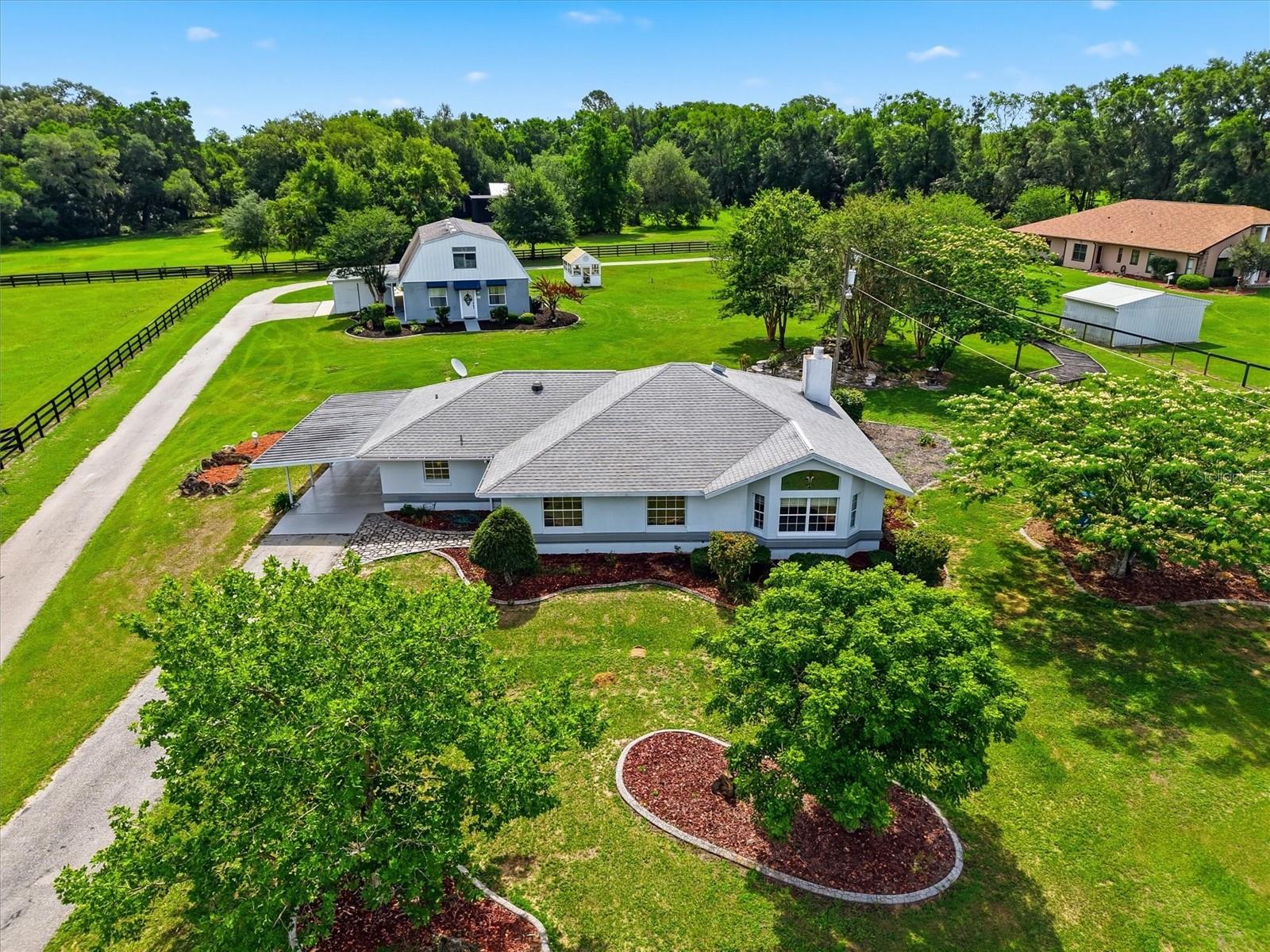 One or more photo(s) has been virtually staged. MULTI-GENERATIONAL LIVING or INCOME PRODUCING PROPERTY. Below Appraisal. This property is a unicorn, NO HOA, NO CDD, NO Deed Restrictions, and NO Flood Zone. Welcome to this PRIVATE Estate retreat — a beautifully landscaped 1.59-acre Gated Property in the heart of Ocala’s Equestrian Community.  Featuring a Main Residency 2 Bed | 1 Bath 1,815 SQFT and a separate Two-Unit Apartment 2 Bed, 1 Bath 1,517 SQFT | 1 Bed, 1 Bath 1,044 SQFT.  The property is FULLY FENCED no climb and top board featuring a large Greenhouse fully equipped with Potting Table, Shifting Station, Electric and Water Hookups. The MAIN RESIDENCE is a FURNISHED 2 BED, 1 BATH, 2-Car Carport home.  Features; Cathedral Ceilings, Window Treatments, Den with Built in Bookshelves, spacious Living room with a Bay Window with an elegant Stained-Glass window above, FIREPLACE (wood and electric capability) Dining Room enhanced with CROWN MOLDING.  The Kitchen has GRANITE Countertops, Cherry-Wood Cabinets, S.S. APPLIANCES, Dual Pantry Closets, Solar Tube.  Tile flooring and Carpet in the Living room and Primary. The PRIMARY features a king-size Tempur-Pedic bed and shares a Jack-and-Jill bathroom with Guest Bedroom/Office. From the Living Room and Primary Bedroom French doors lead to a LAUNDRY ROOM (Maytag W/D) and an Office/Folding area overlooking a peaceful STACKED ROCK WATERFALL POND, SWINGS and a collection of Fruit and Crape Myrtle Trees and a Greenhouse.  GENERATOR HOOKUP TO BOTH RESIDENCES, HVAC (2023), ROOF - Main House (2020).  This unit has Central Heat & Air.  Privately situated behind the main residence, the TWO-STORY APT has so much potential.  PRIVATE DRIVEWAY AND SEPARATE ENTRANCES TO BOTH UNITS.  The FIRST FLOOR APT is FURNISHED, 2 BED, 1 BATH, and a Flex Space plus Handicap Accessible.  With High Ceilings, a Living Room, Family Room, Open Concept Kitchen and Eat in Space in the Kitchen. WHT SHAKER CABINETS, S.S. APPLIANCES, Granite-Look Counters.  LUXURY VINYL PLANK FLOORS throughout.  Bathroom has a Large Handicap Accessible ROMAN SHOWER, plus Water Closet and Vanity.  W/D Hookup.  Flex Space is perfect for a Gym, Office, Craft Room.  Garage for Small Vehicle, Motorcycle, Golf Cart, or Storage. Central HVAC and 3 AC Mini Splits.  The SECOND FLOOR APARTMENT has a Private entrance, this is FURNISHED, 1 BED, 1 BATH and has a Chair Lift in Stairwell for ease of access.  Beautiful Kitchen with Cherry Wood Cabinets, Granite- Look Countertops, WHT APPLIANCES, Dining Room, Den, Window Treatments, Spacious Bathroom with Tub/Shower Combo, Bedroom has Lots of Storage (Attic Space) and Large Walk in Closet.  TILE FLOORS throughout except in Living Room has Laminate Floors.  Private Laundry downstairs next to Stairwell.  Central HVAC.  Shared 2- Car Carport with Garage (for Golf Cart, Small Car, Motorcycle, Lawn Equipment, Workshop, Hobbiest), Double Insulated Attic.  This extraordinary property also includes RV PAD with ELECTRIC and DUMP STATION HOOKUP, and fresh EXTERIOR PAINT plus a GOLF CART, Landscaping Equipment, Tools, a Generator/Arc Welder hookups. Whether you’re an Investor or looking for a FAMILY COMPOUND, this is an incredible opportunity to own close to all the action at HITS, World Equestrian Center (4 Miles), The Equestrian Manor,  In the area of Publix, Starbucks, Gold’s Gym, UF Health Hospital and a short distance to Ocala’s Downtown Square and Farmers Market. Endless possibilities await at this truly one-of-a-kind estate! Schedule your Private Showing Today!