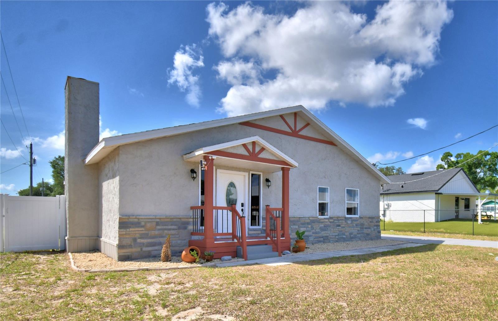 Location! Location! Updated 3 bedroom, 2 bath home is conveniently located halfway between Tampa and Orlando, FL. Nestled within the City of Auburndale's up and coming downtown area, where you’ll find restaurants, bars, local businesses like the new award-winning coffee shop and bakery, and more! Spend your days relaxing at Lake Ariana or at the park downtown and then head across the street for a delicious ice cream treat.  Move right in and enjoy single-level living at its absolute finest!  Upon entering the home, you'll be greeted by a spacious family room that serves as the ultimate gathering room, including soaring vaulted ceilings with exposed beams, cozy carpeting, and a striking 60" electric fireplace as its centerpiece.  At the heart of the home is an eat-in kitchen, a cook’s absolute delight, outfitted with updated appliances, extensive counter space, and ample cabinetry. The primary suite lends itself as a peaceful, private retreat, showcasing its own vaulted ceilings that flood the space with natural light, completed by a generous closet and a beautifully remodeled ensuite bathroom with an oversized shower.  The home's floor plan includes a refurbished second bathroom and two additional versatile bedrooms, perfect for guests, or a home office. You'll love spending time in the back yard as there's a screened- in patio enclosure just begging for weekend BBQ action. The back yard is also enclosed by new vinyl privacy fencing complete with solar lighting and a double gate for easy access from the carport. Come discover this thoughtfully updated home featuring improvements designed for comfort, style, and functionality.  The work's been done for you! Highlights include: new interior doors, baseboards and flooring throughout, including durable luxury vinyl plank flooring and plush carpeting; fresh interior paint; recently replaced HVAC system and ductwork; replaced water heater; and reconstructed chimney.  Schedule a showing today and make 208 Center St. your next home!