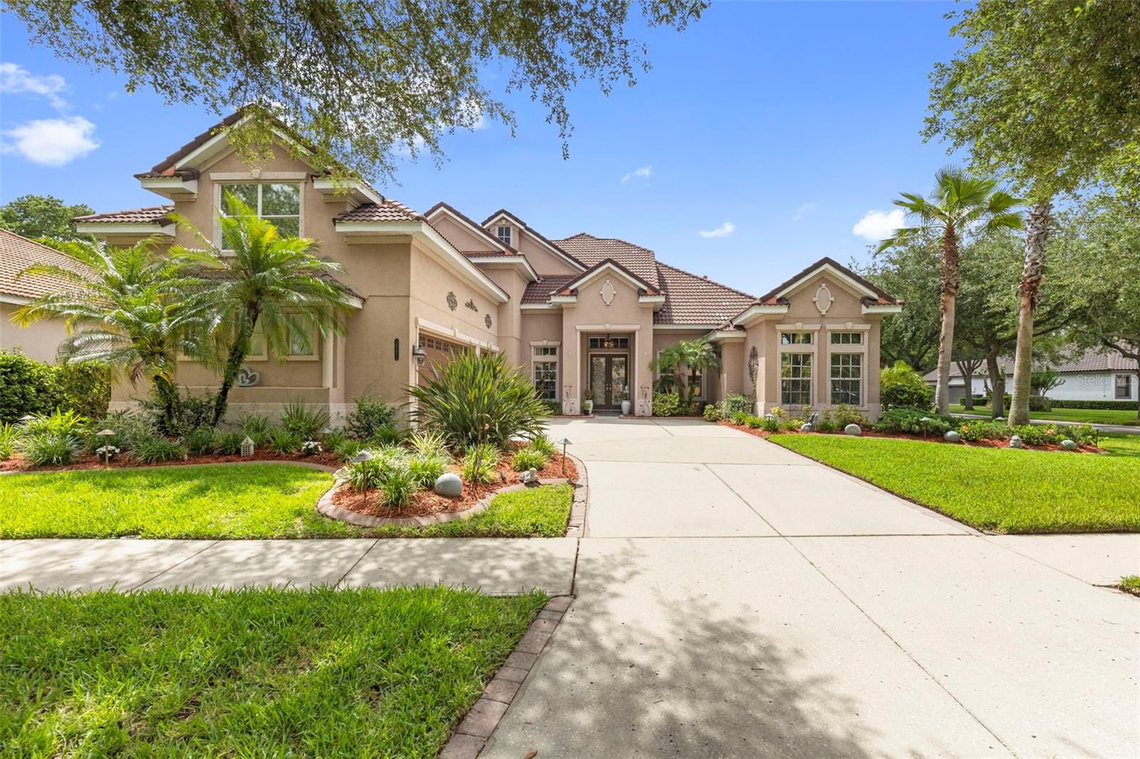 One or more photo(s) has been virtually staged. Positioned on a premium corner lot within the highly sought after gated community of Grand Hampton, this exceptional 5 bedroom, 5 bathroom pool home offers 3,947 square feet of thoughtfully designed living space, luxury upgrades, and timeless elegance. Florida friendly landscaping, landscape lighting, a paver driveway, architectural detailing, and stunning stained glass entry doors create unforgettable curb appeal.

Inside, soaring ceilings, abundant natural light, and an updated crystal chandelier make a striking first impression. The formal dining room, highlighted by its own crystal chandelier, flows seamlessly into the living room with French doors opening to the lanai.

Designed for entertaining and everyday living, the chef's kitchen features 42 inch cabinetry, updated hardware, under cabinet lighting, an updated backsplash, granite countertops, a newer sink and faucet, LG appliances, and a spacious eat in area. The kitchen overlooks the family room and offers direct outdoor access.

The first floor primary suite is a private retreat featuring tray ceilings with crown molding, lanai access, dual California closets, and a spacious ensuite with dual vanities, Corian countertops, a glass enclosed shower with dual shower heads, a jetted soaking tub, and a spacious flex space.

Also on the main level are three additional bedrooms, including a secondary bedroom with engineered hardwood flooring, a custom California closet, and access to a full pool bath. Two additional bedrooms with California closets and updated carpet share a Jack and Jill bath with an updated tub enclosure. A laundry room with cabinetry, utility sink, oversized storage closet, and adjacent built in desk area complete the first floor.

Upstairs, the fifth bedroom features hardwood flooring, a California closet, and a private ensuite bath with an updated tub enclosure. A custom library with glass shelving and extensive storage, a large loft featuring hardwood flooring, and an additional full bathroom provide exceptional flexibility. The loft opens to a private balcony finished with low maintenance Trex decking.

The outdoor living space is a true private oasis. Enjoy a screened lanai with a resurfaced heated pool and spa, covered entertaining areas, a gazebo, mature landscaping, and a fenced pool equipment enclosure. The pool and spa were resurfaced in 2020. The pool heater and pump were replaced in 2024.

The oversized 3 car garage features epoxy flooring, storage shelving, metal tool cabinets, a built in workbench, and upgraded lighting.

Additional updates include a tankless gas water heater (2023), interior repainting, 3M window film, a hardwood staircase, and a washer, dryer, range, and refrigerator replaced in 2022.

Grand Hampton residents enjoy a 24 hour manned gate, resort style clubhouse, 24 hour fitness center, a lagoon pool with water slide, lap pool, tennis courts, basketball courts, parks, lake access, and multiple gazebos. Conveniently located near I 75, I 275, AdventHealth, PHSC, AdventHealth Center Ice, The Shops at Wiregrass, and Tampa Premium Outlets.