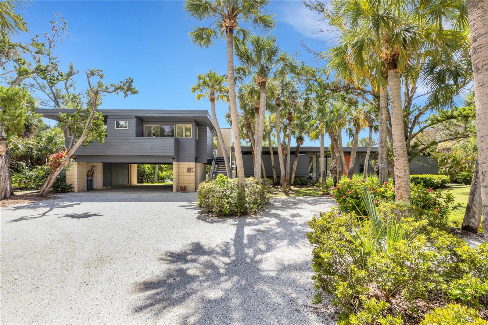 In the coveted Sandy Hook Gulf Beach enclave of only 42 homes, this unique Mid-Century Modern home is now offered for purchase for the first time since 1983. The one-of-a-kind mid-century modern retreat rests on 1.6 acres of serene lakefront adjacent to where Big Sarasota Pass meets the Gulf of Mexico. 
Created by Frank Folsom Smith, a noted member of the Sarasota School of Architecture, this passively designed treasure was crafted from local cypress, oak, terra cotta and Ocala block and sits harmoniously within a lush Florida-native landscape alive with palms, cedars, and blooming wild flora. Nature lovers will delight in the lake along the southern edge of the property, home to a vibrant array of wildlife.
The main residence, built in 1964 and lovingly preserved by its current owner since 1983, features timeless modernist design and abundant natural light through true north and south facing 10-foot glass sliders that welcome daylight. Meanwhile the interiors are shielded from direct sun for restful living. 
The guest house, added in 1987, also designed by the firm, complements the main home, together offering 5 bedrooms, 3 full bathrooms, 2 expansive great rooms, and a rare wood-burning fireplace, perfect for cozy winter evenings.
Outdoors, all residents can enjoy their choice of sun-dappled terraces or shaded garden hideaways beneath more than 120 mature palms and cedars. Thoughtful upgrades ensure comfort and ease in this home's remodeled kitchen with all new appliances, new 

Trane HVAC systems covered by 10-year warranties, a 2025 deep-well irrigation system, and low-voltage outdoor lighting synchronized by the integrated atomic clock for effortless ambiance.

Just a 150-meter stroll west through the trees leads you to Sandy Hook’s exclusive residents-only Gulf beach, a secluded paradise of sugarwhite quartz sand where sea turtles hatch annually and dolphins and manatees play offshore and sunsets paint the sky in vivid color.
Conveniently located near Siesta Village’s boutiques and restaurants, and within easy reach of top-rated Sarasota County schools, The Out-of-Door Academy, and Sarasota Memorial Hospital, ranked among America’s top 50, this home offers the perfect blend of mid-century authenticity, privacy, and coastal lifestyle.

This truly rare architectural offering is where Siesta Key’s natural beauty and Sarasota’s cultural soul meet the timeless artistry of mid-century design.