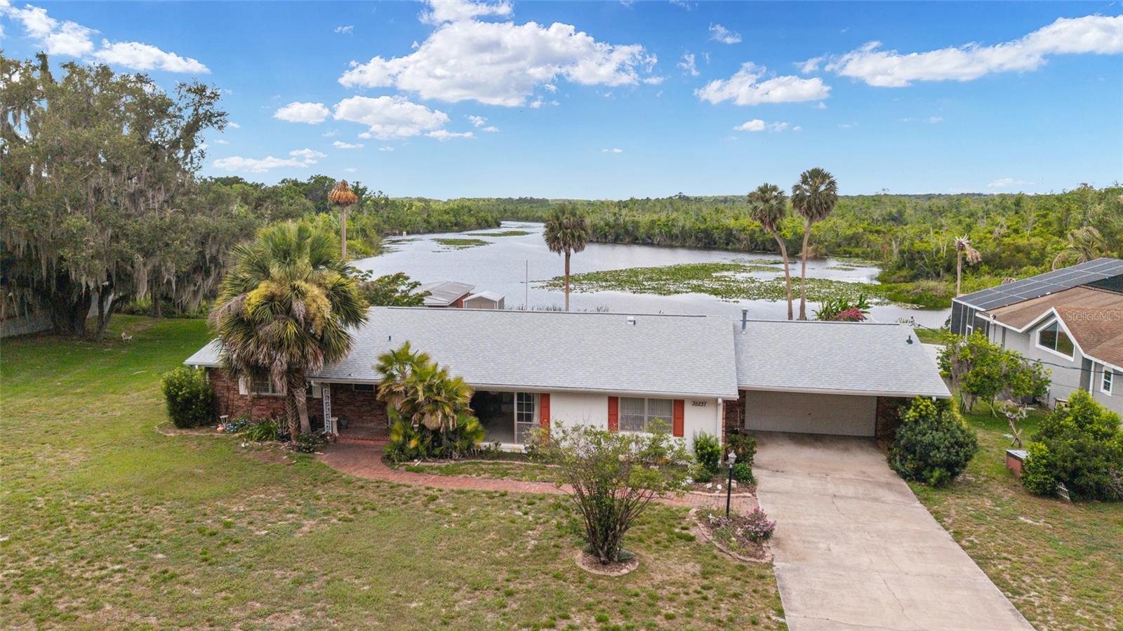 AMAZING VIEWS and OPPORTUNITY on this 4 bedroom 2.5 bath 2 car garage CANAL FRONT home with 200+ feet of prime canal frontage with direct access to Lake Griffin and the renowned Harris Chain of Lakes.  This home sits on an oversized lot of 0.72 acres in Fruitland Park.  Opportunity awaits for boat lovers and fishing enthusiasts to put your touch on this gem. Enjoy evenings on the large screen porch with the beautiful canal view in front of you!  You have not one but two spacious living spaces and also a large dining room.  The primary bedroom includes an ensuite bathroom and a walk-in closet.  The large inside laundry room with utility sink is a perfect place for extra storage and to use as a mudroom. Major updates provide peace of mind, a new architectural roof was installed in January 2025 along with a new metal roof on the back lanai.  The lanai was rescreened in 2025.  The water heater is 07/2020 while the Hvac is newer.  Conveniently located less than 20 minutes from The Villages and just minutes from fantastic shopping, dining, and everyday conveniences, this canal-front property offers the perfect combination of waterfront living, privacy, and endless potential.  Sellers are offering a flooring credit so you can add your personal touch to this waterfront home.