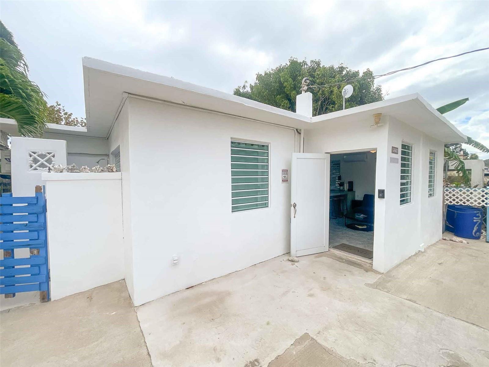 This three-bedroom concrete home is located in Esperanza—once a humble fishing village and now a dynamic hub of restaurants, beachgoers, and travelers from around the world who come to experience Caribbean Life at its most authentic. Just a short trip to the beloved Malecon, a waterfront boardwalk lined with colorful bars,  music, and some of the best oceanfront dining you'll find in Puerto Rico. Whether you're heading out for fresh fish tacos and mojitos or returning from an evening paddle through the world-famous Bioluminescent Bay, everything you want is right here.

Now, let’s talk about La Perla del Mar itself. This home is designed for island living—simple, efficient, comfortable, and made to handle the elements. The entire structure is concrete, with durable tiled floors throughout that are both low-maintenance and cool underfoot. 

The kitchen is built with practical concrete counters and a connected island, perfect for chopping fruit in the morning or mixing cocktails in the evening. The barstools make it an easy gathering place, whether you’re cooking, working remotely, or hosting friends. Each of the three bedrooms is fitted with air conditioning, ensuring restful sleep no matter the season. The home also includes a washer and dryer, and a dedicated owner’s closet adds a layer of convenience and security for those who plan to rent it out.

What really sets this property apart, though, is the outdoor lifestyle it encourages. On the side of the house, there’s an outdoor shower—ideal for rinsing off after a swim or boogie-boarding session. Out back, you'll find a spacious concrete deck built with entertaining in mind. It features a sturdy concrete bar and is surrounded by lush banana trees and other tropical fruit-bearing plants. This is the kind of space where guests linger well into the evening, where laughter and music mix with the rustling of banana leaves overhead.

With a layout that includes one indoor bathroom, a half-bath accessed from the deck, and that outdoor shower, it’s easy to keep the inside of the house clean while everyone enjoys the outdoors. It's a smart setup.

La Perla del Mar is already a proven income property, with a strong rental history of over $39,000 annual gross income. Whether you're looking to keep that momentum going as a short-term rental or transition to a long-term lease—or even use it as your own full-time residence—this property offers incredible versatility. It has title, is fully functional, and is located in a high-demand tourism zone. This one checks a lot of boxes.

If you’ve spent any time researching Vieques homes or exploring the world of Puerto Rico real estate, you already know that properties like this—affordable, income-producing, and close to everything—don’t come around often. This home puts you close to Esperanza’s best features, including some of Vieques Island’s most beautiful beaches. You’ll be just minutes from Sun Bay, Media Luna, and Navío Beach—each offering soft sand, turquoise water, and that magical sense of escape that makes Caribbean living so alluring.

So whether you're seeking your next Caribbean investment, planning for your retirement in the tropics, or ready to commit to the Caribbean Lifestyle full-time, La Perla del Mar deserves your attention. It's ready to go, full of personality, and located in one of the most sought-after areas for Vieques properties.