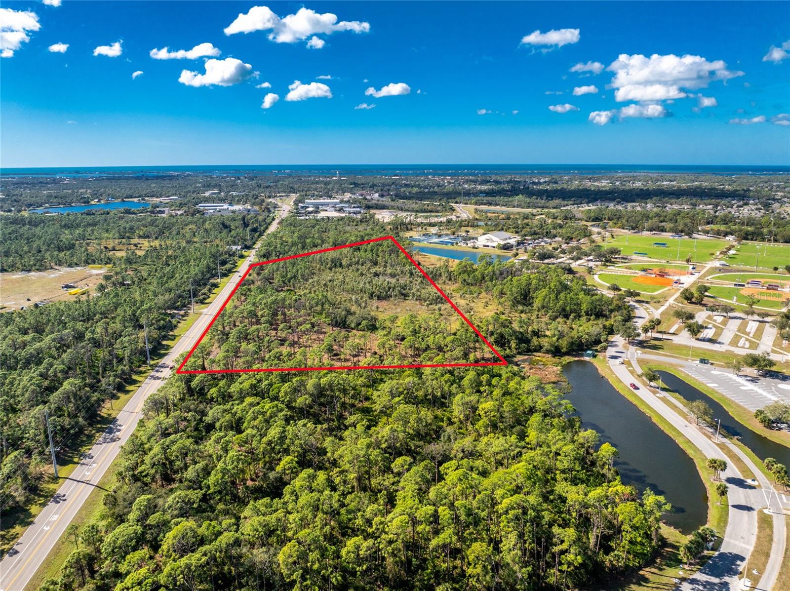 Rare opportunity to acquire a highly visible 15 acre commercial development site along South River Road, zoned ILW - Industrial Light & Warehousing, within the rapidly growing Wellen Park Corridor. The property backs directly up to greenspace and retention ponds located within the Sarasota County owned Englewood Sports Complex, providing a defined rear boundary and buffering from adjacent uses. The property offers approximately 1,000 feet of frontage along River Road. The site includes approximately 6.03 acres of usable land following approved wetland mitigation, with all non-developable acreage located at the rear of the property. This layout allows for an efficient building footprint and strong road frontage. Wetlands and mitigation areas are approved and clearly delineated under the current civil plan, offering clarity and certainty for future development. Positioned on a major arterial roadway, the property benefits from excellent visibility and traffic exposure and has received positive feedback from engineering and trade professionals regarding its development potential. Utilities are readily accessible, with electric service at the property line, water connection on the south side of South River Road, and planned sewer service via a lift station connecting to an 8-inch force main through the Englewood Water District. The substantial buildable footprint is well suited for a wide range of commercial or light industrial users seeking visibility, accessibility, and a strategic location within one of the area’s fastest-growing corridors. The property is located less than one mile from where South River Road transitions into Dearborn Street, near the local post office providing you plenty of convenience and accessibility for your commercial project.