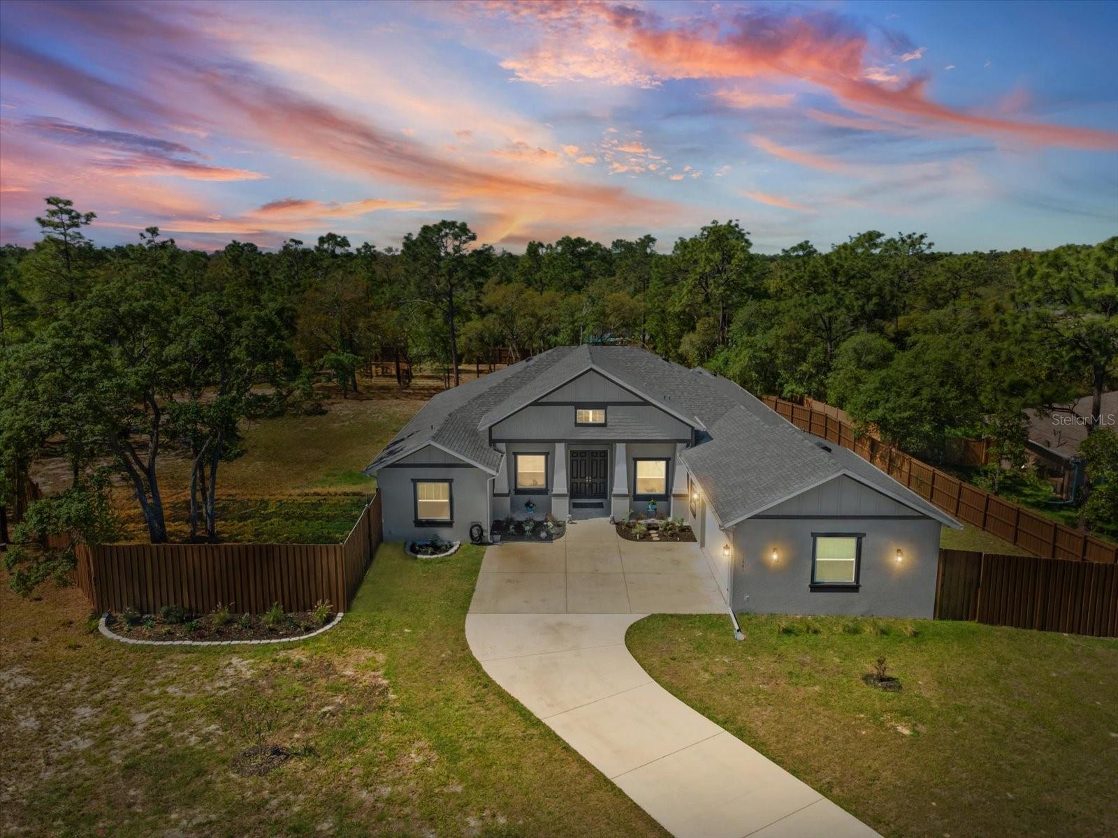 Move-in ready custom-built home on 1.27 fully fenced acres offering 5 bedrooms, 3 bathrooms, and a thoughtfully designed open floor plan. This newly constructed residence combines modern finishes with functional living spaces throughout.
Interior features include coffered ceilings, expansive sliding glass doors, and an open-concept layout ideal for both everyday living and entertaining. The kitchen is equipped with an oversized granite island, Viking propane cooktop, built-in convection oven with microwave, ample cabinetry, and an adjacent eat-in dining area.
The primary suite includes dual vanities, a zero-entry walk-in shower, a soaking tub, and a large walk-in closet. An adjoining sitting area offers flexible use as an office, lounge, or additional sleeping space. Three additional bedrooms are located on one side of the home, while a split fifth bedroom features its own ensuite bath and walk-in closet, suitable for guests or multi-generational living.
Additional features include an oversized garage with a climate-controlled bonus room, a large walk-in pantry with media panel, and a dedicated laundry room. The property also includes a buried propane tank (suitable for generator or future outdoor kitchen), and is pre-plumbed for a water softener system.
Exterior highlights include a covered patio overlooking the private, fenced acreage, offering space for outdoor living, entertaining, or future pool installation.
Conveniently located near local amenities, including shopping, dining, medical facilities, Weeki Wachee Springs, Pine Island, and the Suncoast/Veterans Expressway for commuting access.
