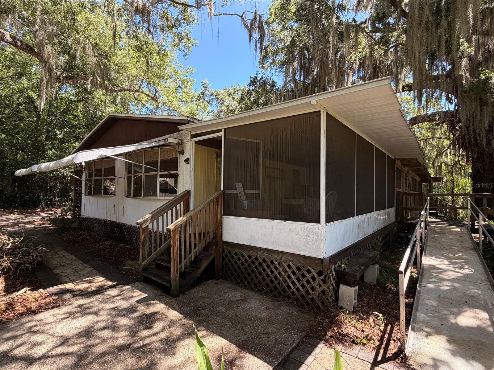 BACK ON THE MARKET & SWEETER THAN EVER AT $190,000! Buyer's financing fell through, creating a rare second chance to claim this incredible coastal property at an unbeatable new price point! BONUS: The private septic system was just completely serviced and has already fully PASSED inspection within the last few weeks—saving your buyer time, money, and providing total peace of mind from day one!
Nestled on a massive, deep 1.11-acre lot on a quiet road, this property offers an exceptional blend of complete privacy, Old-Florida natural beauty, and ultimate outdoor freedom. The expansive land features a stunning canopy of historic, old-growth live oaks—including one of the largest and most majestic trees in all of Oak Hill—and is bordered directly to the east by Indian Creek, providing a peaceful, natural water boundary.
Walk into the backyard and cross your own private wooden footbridge over the creek to a unique sliver of land that connects straight into the boundaries of River Breeze Park! While the creek itself is perfect for kayaks and nature watching rather than large motorized vessels, you are less than 3 minutes away from one of Volusia County’s absolute premier public boat ramps at River Breeze Park, offering effortless, world-class access to the world-renowned waters of the Mosquito Lagoon.
THE FREEDOM: Located in unincorporated Volusia County with NO HOA, you have total freedom to utilize this deep lot to its fullest potential. Equipped with its own private well and newly certified septic, you enjoy maximum independence with zero city water or sewer bills. Bring your trucks, trailers, RVs, and boats—there is more than enough room for all of your toys, or space to live comfortably while planning a future custom build.
THE POTENTIAL: The existing structure is a spacious 4-bedroom, 2-bathroom double-wide mobile home framed by a massive, sweeping wrap-around porch on the south and east sides—perfect for taking in the cool coastal breezes and serene views. The home is entirely renovation-ready and is being sold strictly AS-IS. It requires updates throughout, including drywall replacement, making it the ultimate blank canvas to build instant sweat equity or remodel into the premier local fishing camp of your dreams.
Opportunities to own over an acre of certified, coastal-adjacent land this close to the water for under $200k do not last. Bring your tools, bring your vision, and grab this second chance before it’s gone!