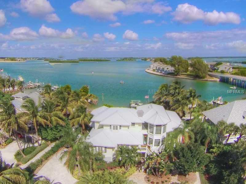 SANDY BEACH, DEEPWATER DOCK AND HEATED POOL-Award winning residential designer, Gerald R Maki, and long-time builder, Jack Curley, collaborated to create this beach-inspired custom home. Intended to take advantage of the vibrant water vistas, this design incorporates stylish windows, turrets and gables into an impressive, open floor plan ideal for entertaining guests or extended family. Spacious living room presents 20' ceilings, custom wood features and striking spiral staircase. First class kitchen is well equipped to handle a crowd with granite counters, stainless appliances and crafted wood cabinets. Main floor also includes combination family room and dining room, two en suite bedrooms complete with walk-in closets, and waterside all-weather porch with sliding glass doors. Privacy abound for the homeowners in the second floor owner suite, featuring a built-in desk/office area, spacious loft sitting area, and luxurious master bedroom with bead pine coved ceiling, spacious bathroom and sunny deck looking out towards the gulf. Heated pool and spa just steps from the beach, and abundant gardens with peaceful backyard seating enhances the allure of this property. Wired for an interior elevator, first floor has oversized two car garage with separate golf cart entrance and sizeable bonus space. Deep water dock with two lifts complete this fantastic island package.