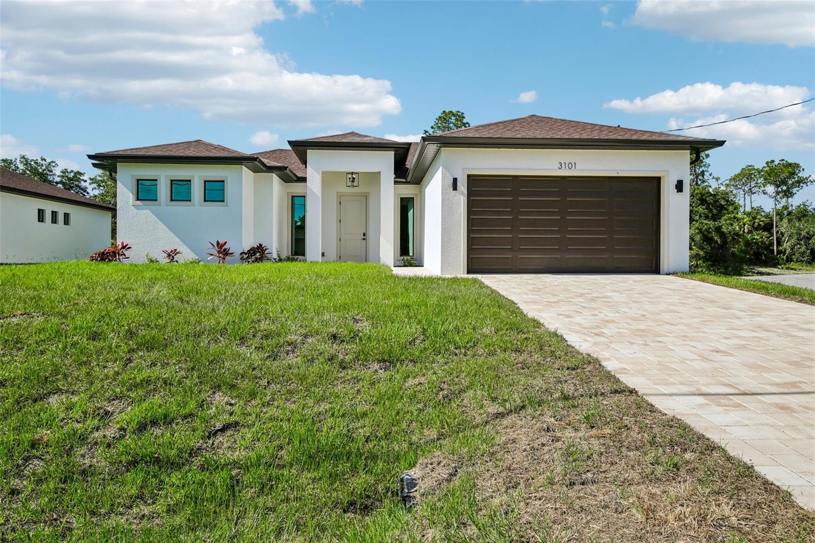 One or more photo(s) has been virtually staged. Oversized, just over 14,000 SF lot! The living space spans 1,869 square feet and includes a garage, entrance area, and an oversized lanai, bringing the total covered area to 2,680 square feet. With three bedrooms and two bathrooms, this home offers comfortable living for a family. Inside, you'll find high ceilings, with tray ceilings in the living room and master suite elevated to 10 feet, creating an open and spacious atmosphere. Large energy-efficient, impact windows flood the interior with natural light, complemented by a massive 4-panel sliding glass door in the living room and an 8-foot French door leading from the master suite to the lanai. The kitchen is a chef's dream, featuring stainless steel appliances, upgraded cabinets with soft-closing hardware and crown molding, quartz countertops, full backsplash and an oversized island with a breakfast bar. The master suite is a true retreat, offering dual walk-in closets and a luxurious master bathroom with his and hers vanities, an oversized double walk-in shower with rain-head and handheld showers, and a freestanding soaking tub. The house is adorned with ceiling fans and chandeliers throughout, boasts a smart garage door opener, and features a driveway, footpath, and entrance areas paved with pavers. Additional highlights include shelving in closets, full front gutters, 8-foot front door and sliding glass doors, Carrera-style interior doors with contemporary square casings, and high-end luxury vinyl tile flooring throughout the house. This home offers a blend of modern luxury and comfort in a spacious and meticulously designed setting, enhanced by its picturesque oversized lot.
