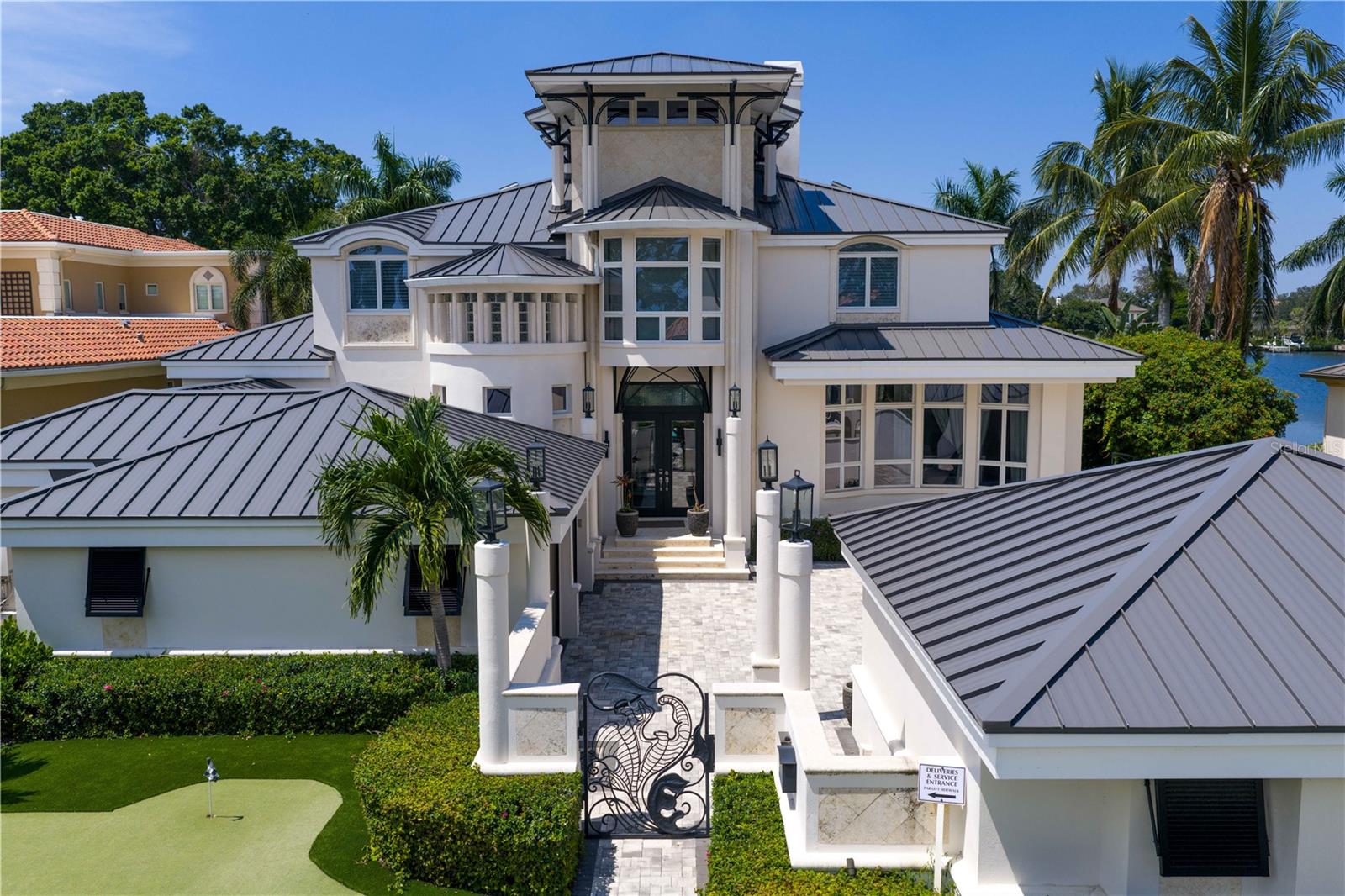 Welcome to this exquisite estate on Coffee Pot Riviera, a half-acre lot on a protected inlet of Tampa Bay.  Right away you are drawn to the vine-inspired wrought iron gates making a striking first impression to the property's entrance. The overall style of the home pulls together unique architecture elements of organic, nature-inspired design. A jaw dropping grand entrance blends a functional structure requirement with a creative artistic design of columns that resemble the natural form and texture of trees allowing this three-story open living space to seamlessly integrate with the waterfront landscape. The tongue-and-groove ceiling of this space is reminiscent of a boat's hull, which enhances the spacious, open airy feel of the home, like the feeling of being on a luxury yacht. Bringing this all together, creates a magnificent three-story wall of windows flooding the house with natural light, offering views of the water and creating a seamless connection between the indoor and outdoor spaces. It’s simply stunning!  Next you are drawn to the expansive outdoor area which was carefully designed to provide much-needed shade and comfortable, covered living space that connects beautifully to the extra large backyard, large infinity pool and waterfront. A grandfathered boat house offers a rare and valuable feature to protect your watercraft. Everything has been updated and enhanced by the current owners with the addition of new flooring throughout, updated bathrooms and kitchen, brand new metal roof and ALL (three) new AC units.  An added bonus is the primary bedroom being on the first floor as well as another bonus room that could be used as a bedroom with a full bath, media room or office. The other guest bedrooms are all on the second floor. A four car garage (two have been converted to a gym) gives you the flexibility for extra cars or a workout space.  This sophisticated design combined with Florida's tropical landscape will give you a luxurious yet comfortable living experience in the heart of fabulous St Pete!  No flooding. Ready for immediate occupancy. Can be sold furnished.  All furnishings new from Restoration Hardware, Arhaus, and Timothy Oulton.