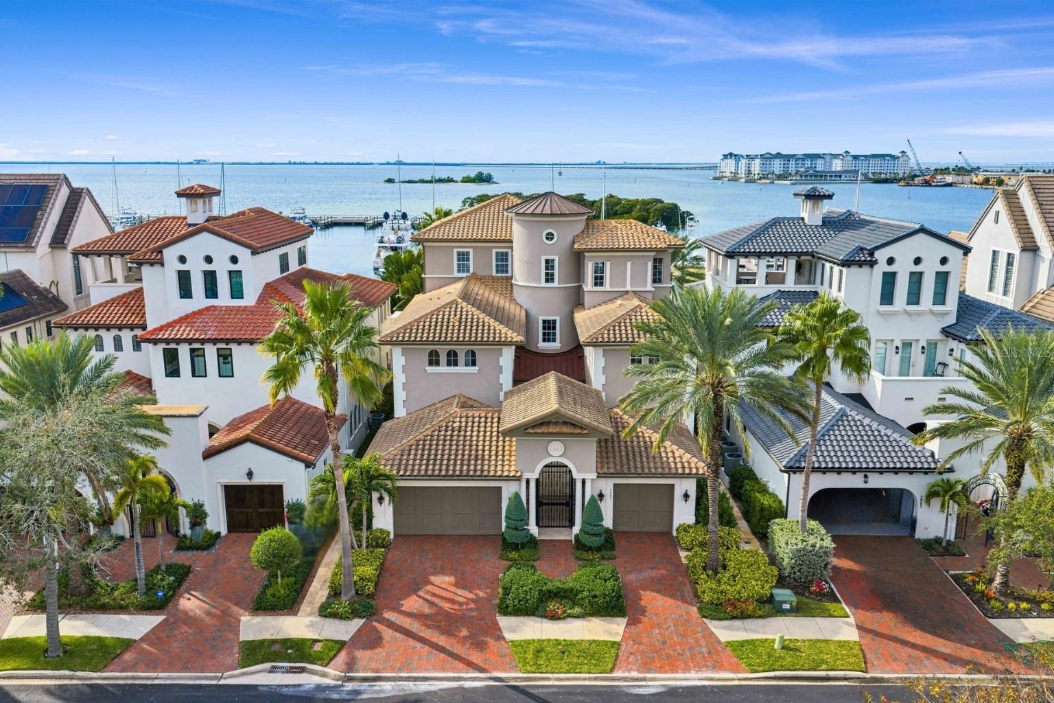Experience refined open waterfront living in this exceptional residence within the coveted Westshore Yacht Club. This five-bedroom, six-and-a-half-bathroom home offers thoughtfully designed living across multiple levels and includes two private studies, one featuring custom built-ins and a second study located off the primary bedroom, complete with a walk-in closet and access adjacent to the primary suite’s private balcony—ideal for a secluded workspace or private retreat. A private gated courtyard entrance welcomes you into a dramatic three-story foyer, immediately setting the tone for the elegant interiors that follow. Perfectly positioned overlooking the Westshore Yacht Club Marina and Tampa Bay, the home captures breathtaking open water views from multiple vantage points, including the private balcony off the primary suite and an additional private balcony on the third-floor fifth bedroom/bonus room. Luxury amenities are seamlessly integrated throughout, including a wine cellar accommodating approximately 700 bottles, a private elevator, and a dedicated home cinema (accounted for as the fifth bedroom/bonus room). Along with multiple balconies, outdoor living is equally impressive, featuring an infinity pool overlooking Tampa Bay and a fully equipped outdoor kitchen—perfect for hosting while enjoying the serene waterfront setting. Evenings are defined by spectacular sunsets over Tampa Bay, with ever-changing hues of gold and crimson casting a glow across the open water and surrounding marina.