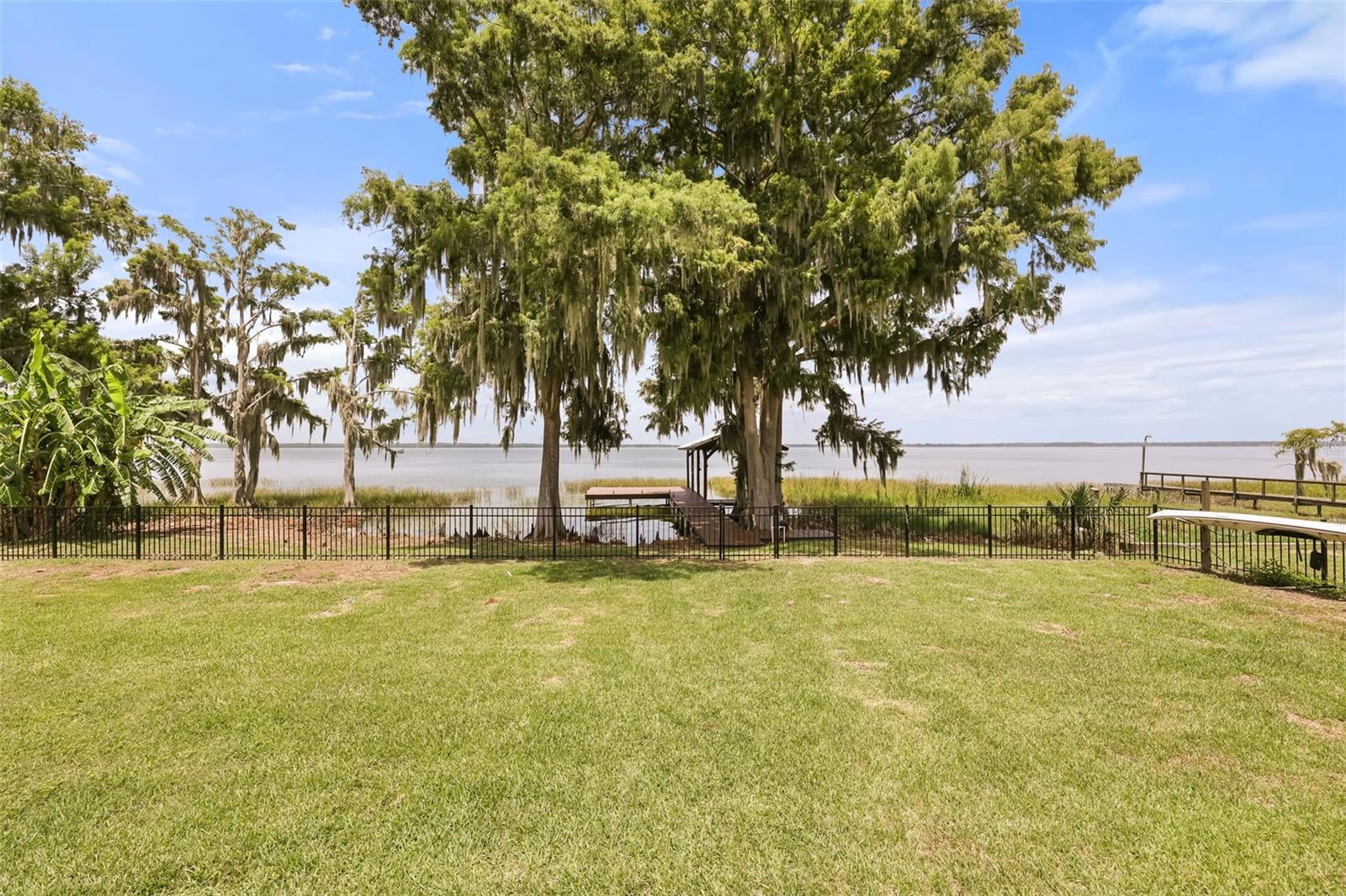 Virtually Staged. No HOA and over 100 feet of private shoreline on Lake Eustis, one of the largest lakes on Central Florida's famed Harris Chain of Lakes. Set on a half-acre homesite, this lakefront home pairs everyday comfort with the kind of big-water access most Florida buyers only dream about.
Inside, cedar beams and a striking stone fireplace anchor the dining room, while timeless Chicago brick in the entryway and lanai gives the home warmth and character all its own. Thoughtful updates, including luxury vinyl plank flooring and recessed lighting, keep the home fresh and move-in ready. The spacious primary suite sits lakeside with its own sitting area and private lanai access, so you wake up to water views every morning. Three additional bedrooms flex easily for family, guests, or a home office.
Outside is where this property truly delivers. Added in 2024, the saltwater pool and expansive wood deck overlook the lake, creating the setting for weekend entertaining or a quiet evening swim as the sun drops over the water. At the shoreline, your private dock and boathouse with electric lift put the entire Harris Chain at your doorstep.
That access changes how you live. Cruise the legendary Dora Canal, once called the most beautiful mile of water in the world, and tie up for lunch or sunset dinner on the waterfront in downtown Mount Dora, with its shops, festivals, and historic charm. Head the other direction down the Dead River to Lake Harris and downtown Tavares, America's Seaplane City, where lakeside restaurants, live music, and waterfront events are all reachable by boat. Eight connected lakes mean year-round boating, championship bass fishing, sandbar afternoons, and some of the best sunsets in Central Florida, all from your own backyard.
Lakefront living on the Harris Chain starts here. Schedule your private tour today.