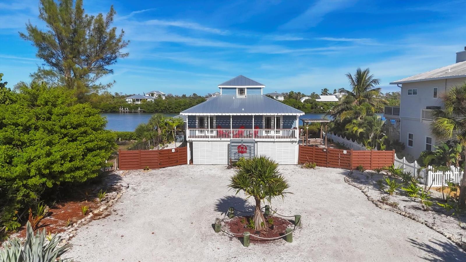 Upon arrival to this beach house, you'll instantly feel the island vibe.  Home has updated roof, siding, and has IMPACT windows and doors. Upon entering the home, you'll immediately notice the spacious open floor plan as well as the artistic flair that flows throughout the entire property.  The updated kitchen has sparkly white waterfall countertops with breakfast bar that seats six, white wooden cabinetry with an abundance of storage space, plus a wooden accent island. There is a stainless steel refrigerator, electric convection stove with double oven, dishwasher & sink.
There is coretec plus vinyl flooring throughout the home.  The living and dining room offer a very relaxing atmosphere with 6-1/2' by 20' of glass walls and door bringing in views of the amazing 400-foot-wide Kettle Harbor Waterway.  This truly brings outside into your living space.  Yes, you can truly see manatees and dolphins on a regular basis.  The on-suite and second bedroom have private access to a 7' x 20' deck with a pergola for sunset viewing.   Access to the third bedroom is by way of a beautiful wooden sap cherry staircase. It offers a half bath and its own private balcony overlooking Kettle Harbor.  The outdoor oasis is second to none.  A salt water pool is 17' x 28' and has a large covered seating and dining area.  The ground level offers a air conditioned bonus room 11x18 and a full service  pool bath.  This area also offers an elevated outdoor wooden, screened kitchen & bar  cabana with beautiful water views.  To add to your outside enjoyment there is a pergola style swing bed,
A 250 foot circular wooden deck for poolside sun enjoyment.  For boating pleasure there is a wooden dock and a 10,000-pound boat lift.  There are no bridges on Kettle Harbor and offers direct access to the ICW and Gulf.  This home also has deeded beach access, just a quick walk or golf cart ride away.